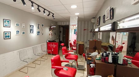Interior de Peluquería De Hombre Y Niños Los Remedios en Sevilla, Andalucía, ES, con asientos rojos y decoración moderna.