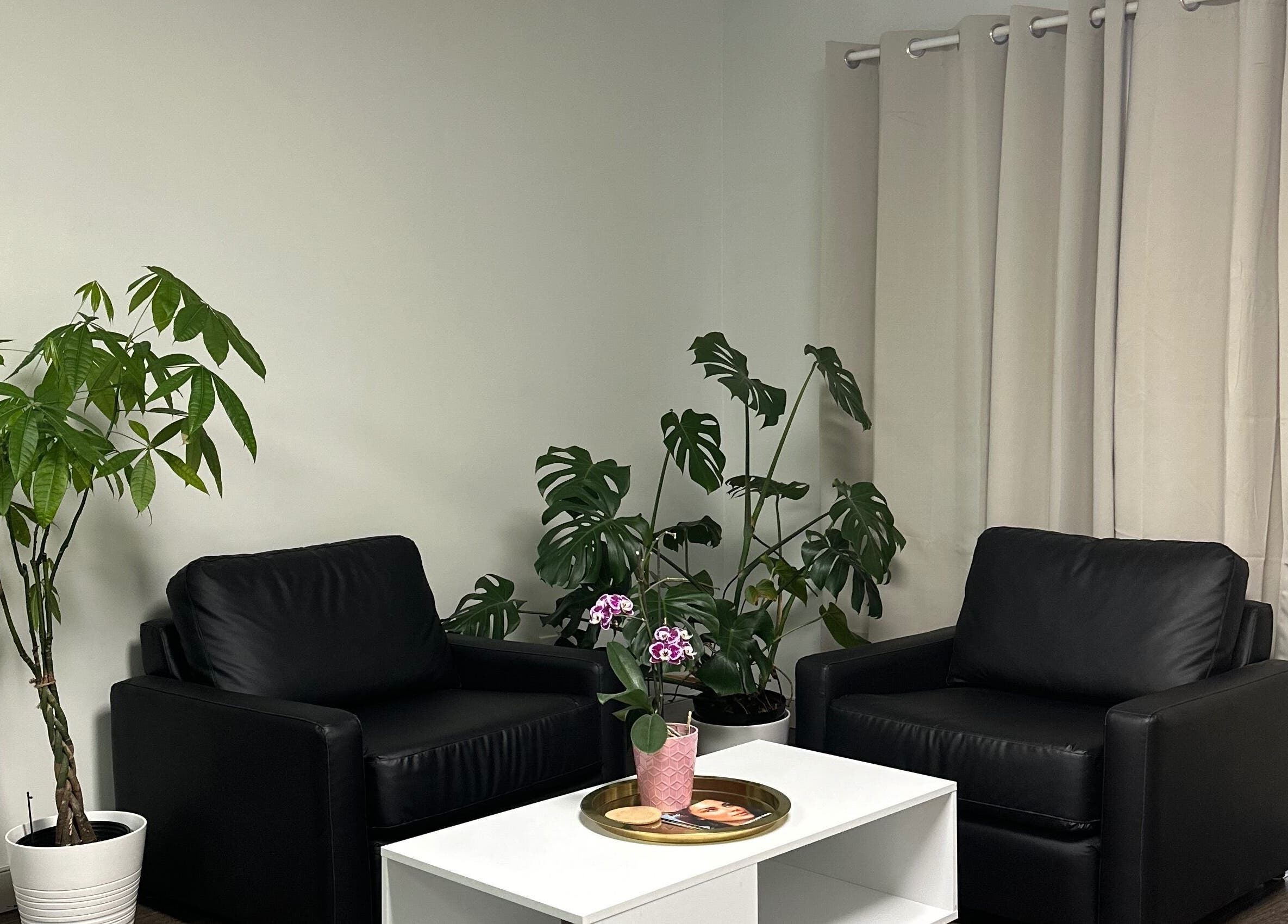 Relaxing waiting area with black chairs and greenery at KALOLOGY in Winnipeg, Manitoba, CA.