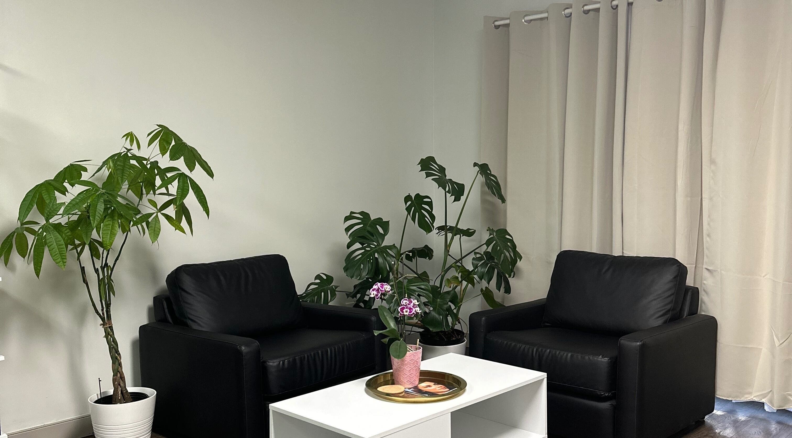 Relaxing waiting area with black chairs and greenery at KALOLOGY in Winnipeg, Manitoba, CA.