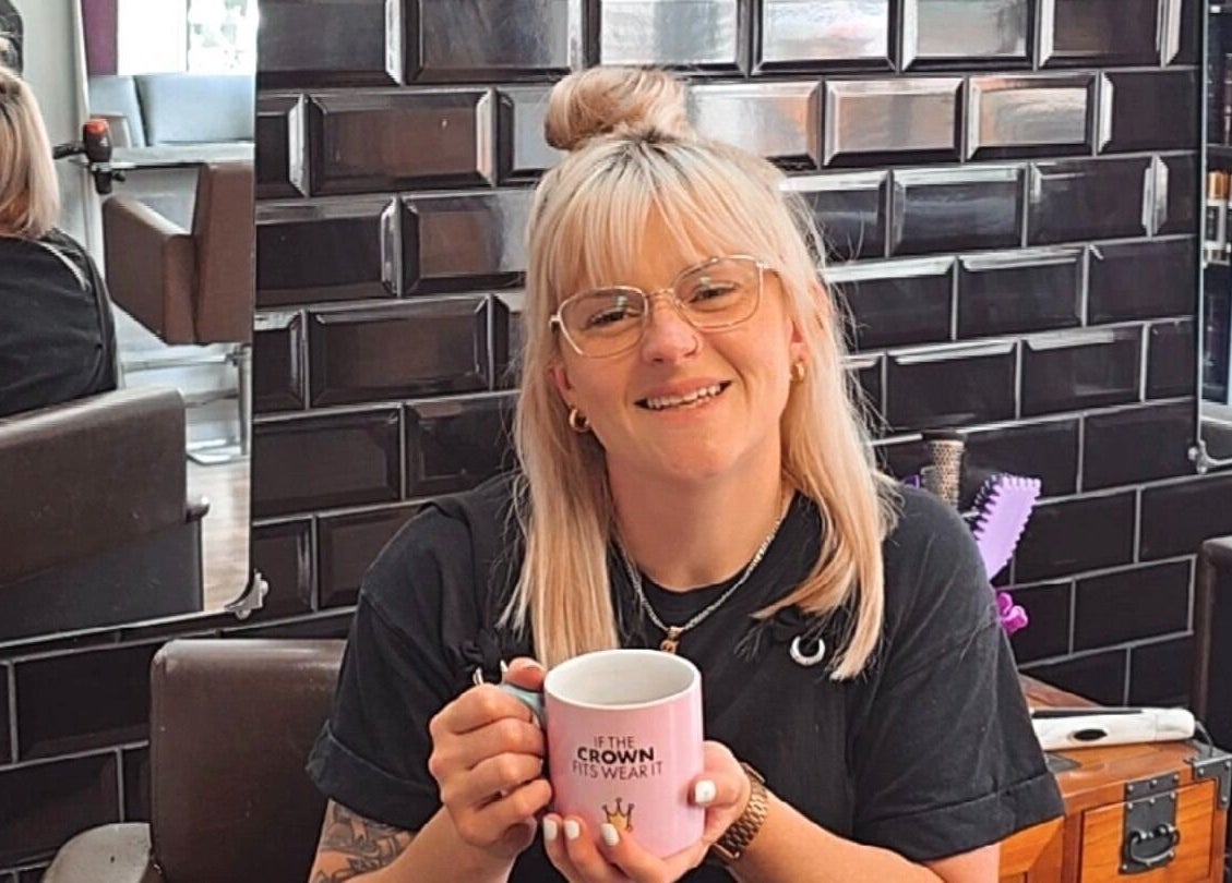 Smiling individual holding a mug at Alice Woolf in Gloucester, England, GB.