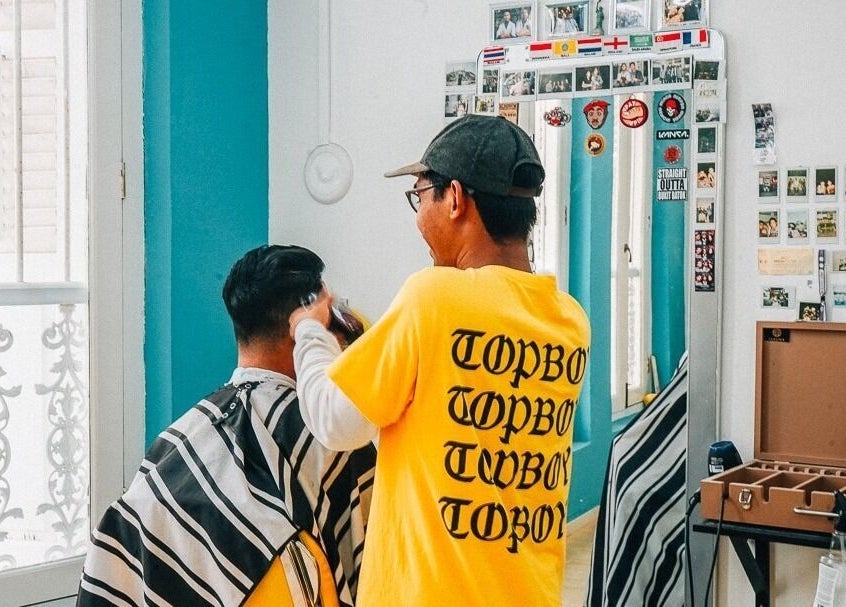 Barber styling customer at Bodeiga, Singapore, Singapore, SG. Vibrant ambiance, expert grooming.