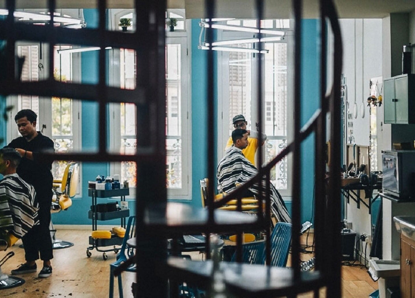 Interior of Bodeiga salon in Singapore, Singapore, SG with barbers styling clients' hair.