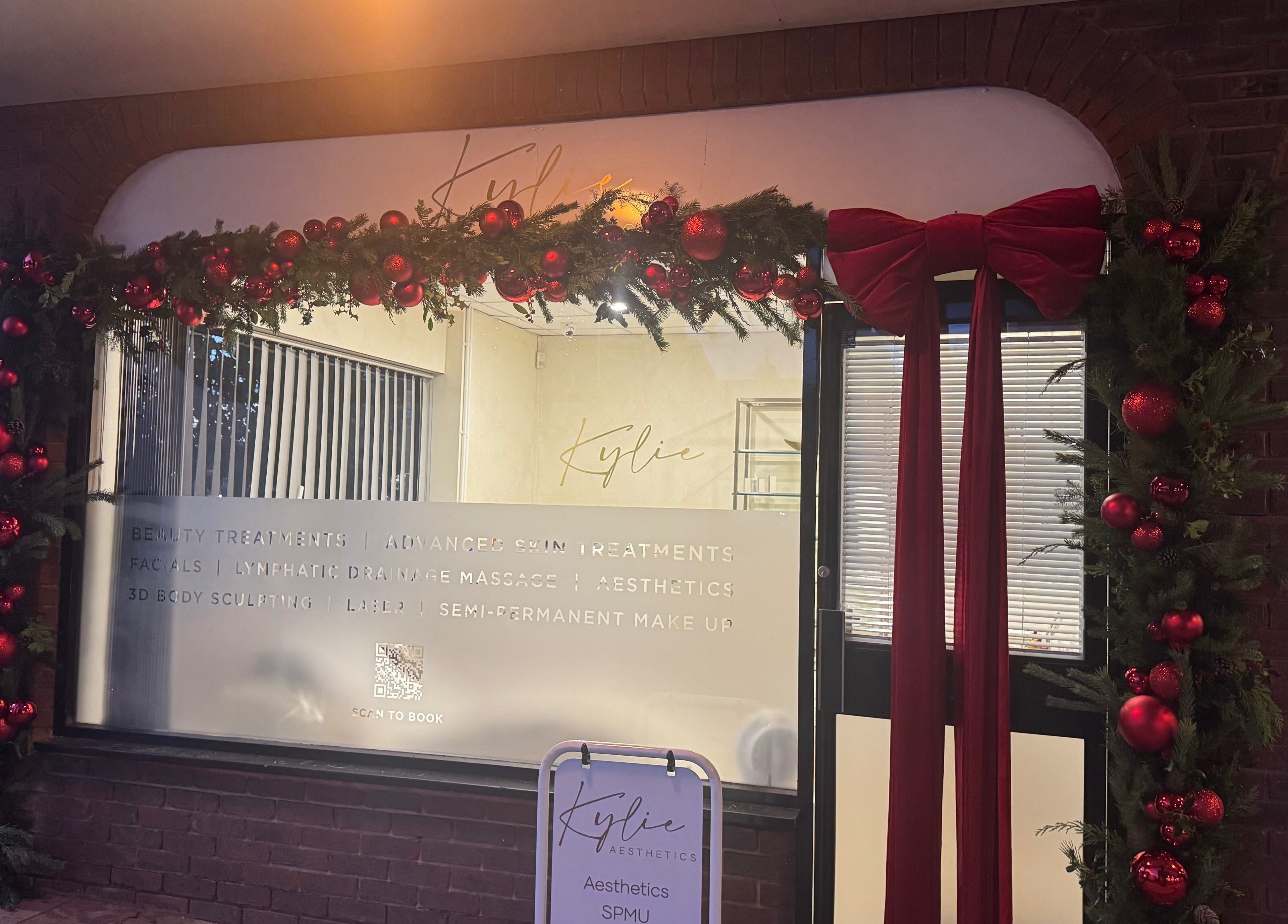 Entrance to Kylie Aesthetics in Christchurch, GB, decorated with festive garlands and red ornaments.