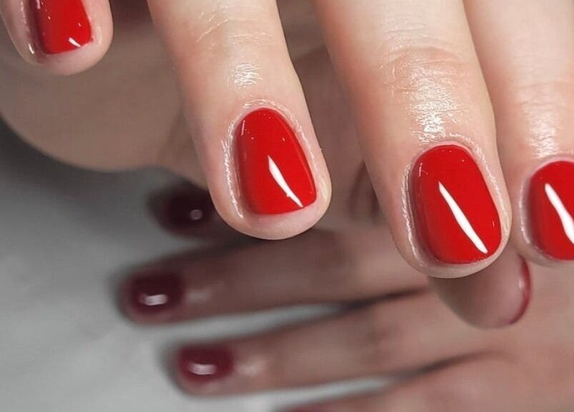 Close-up of vibrant red manicure at Tina Jane, Urmston, England, GB, showcasing glossy nail finish.