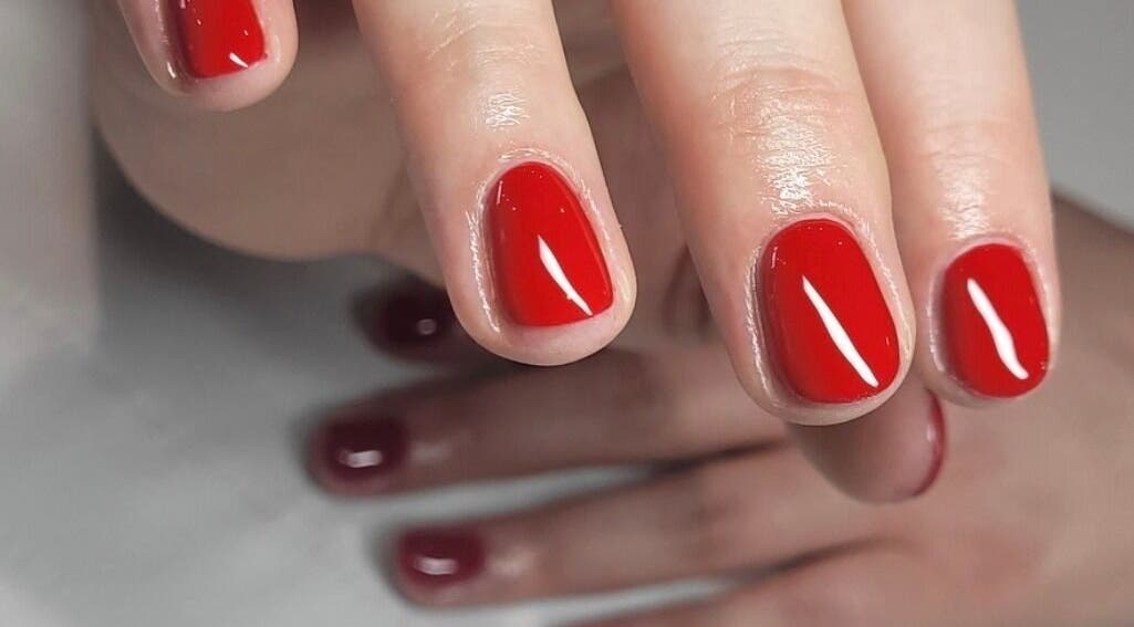 Close-up of vibrant red manicure at Tina Jane, Urmston, England, GB, showcasing glossy nail finish.