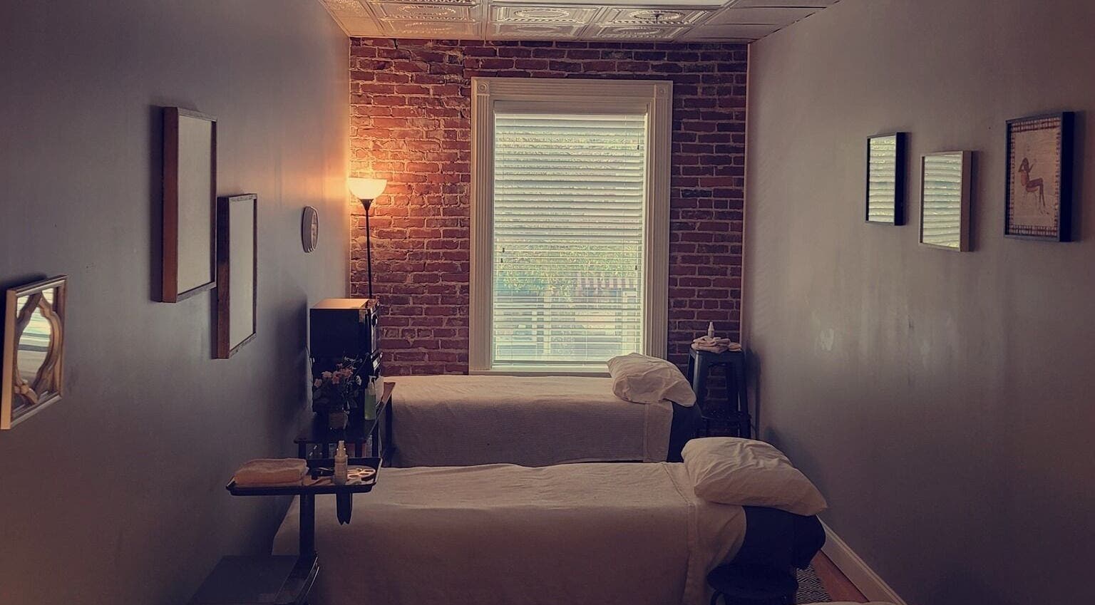 Relaxing twin massage beds at The Beauty Bar LG, LaGrange, Georgia, US with warm brick and soft lighting.