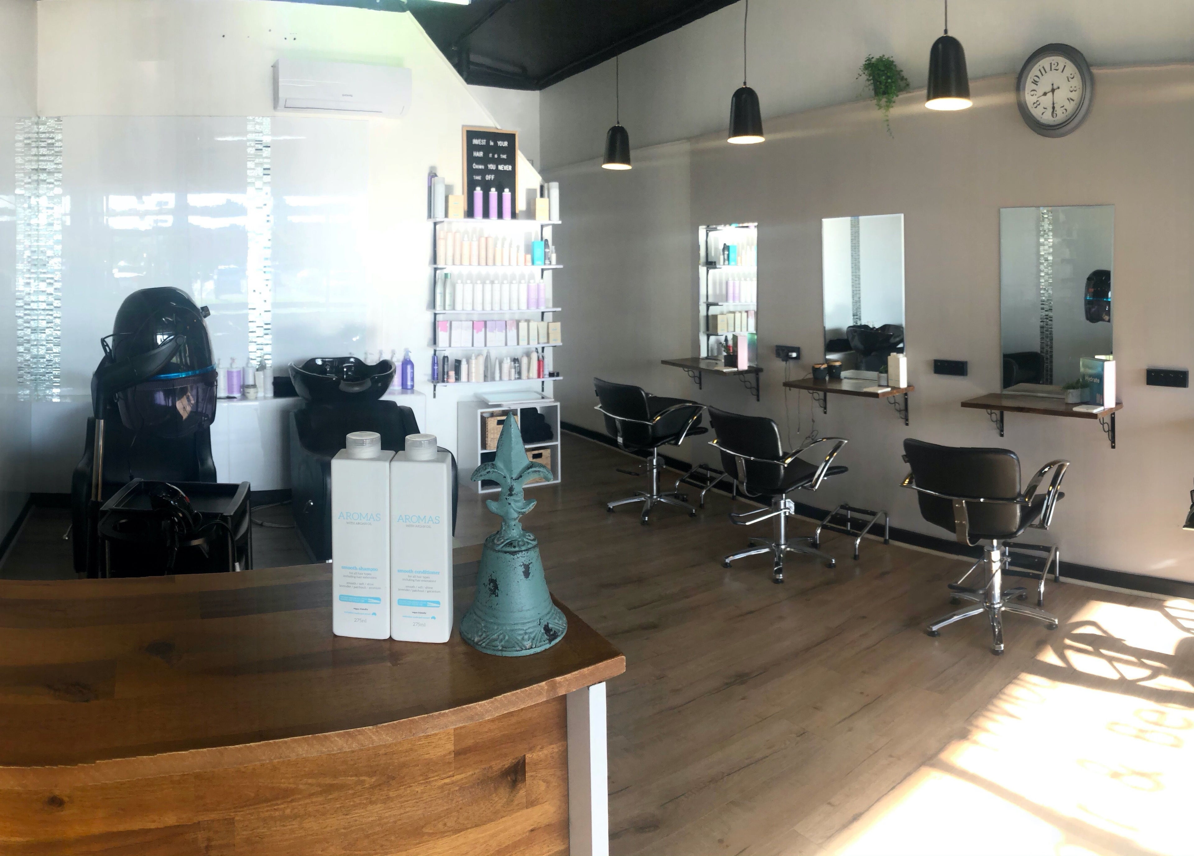Modern interior of Envious Hair And Beauty, Figtree, New South Wales, AU, showcasing styling chairs and products.