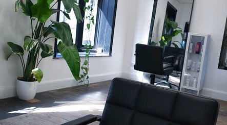 Modern salon chair and lush plant at The Watt, Downham Market, England, GB, showcasing sleek interiors.