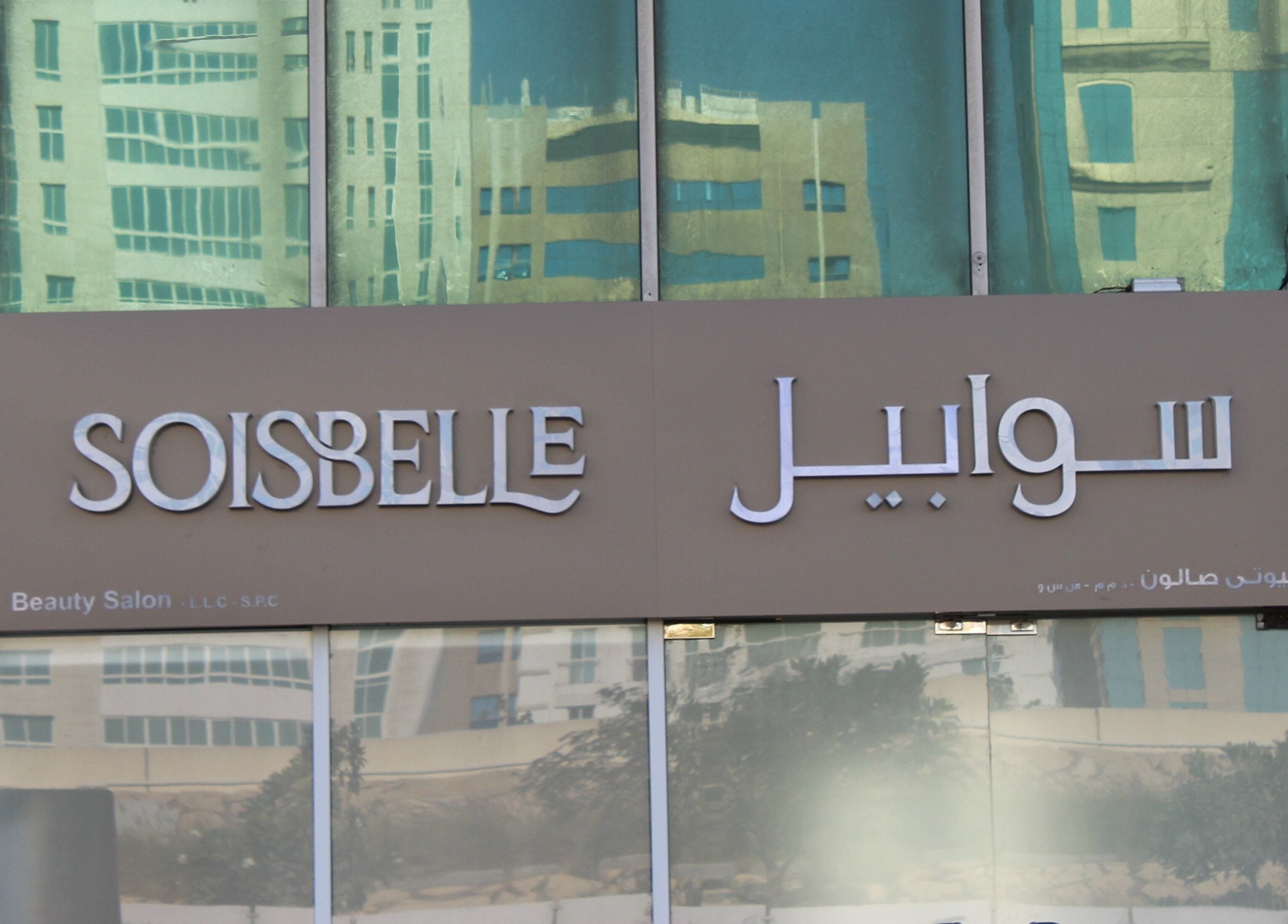 Exterior signage of Sois Belle Salon in Abu Dhabi, AE, with reflections of nearby buildings.