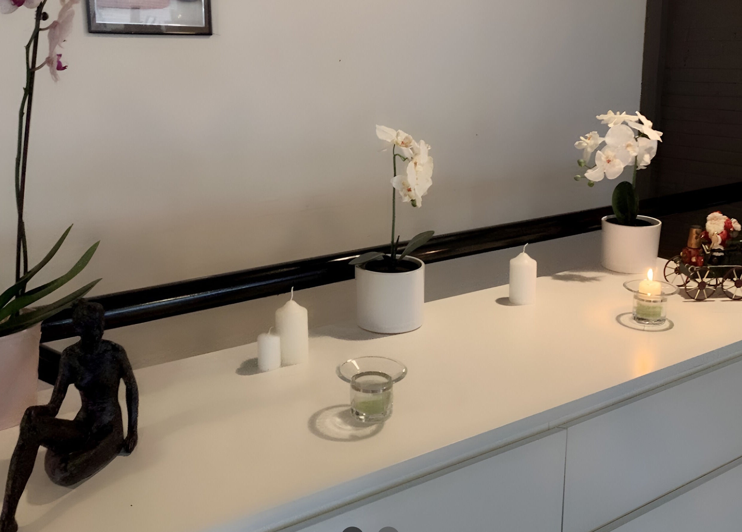 Elegant dekoration hos Patty Wellness Thai Massage i Skanderborg, DK med lys og orkideer på en hvid kommode.
