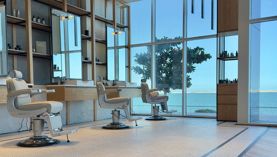 Elegant interior of Akin Barber & Shop AbuDhabi By The Creek showcasing barber chairs with a sea view, Abu Dhabi, AE.