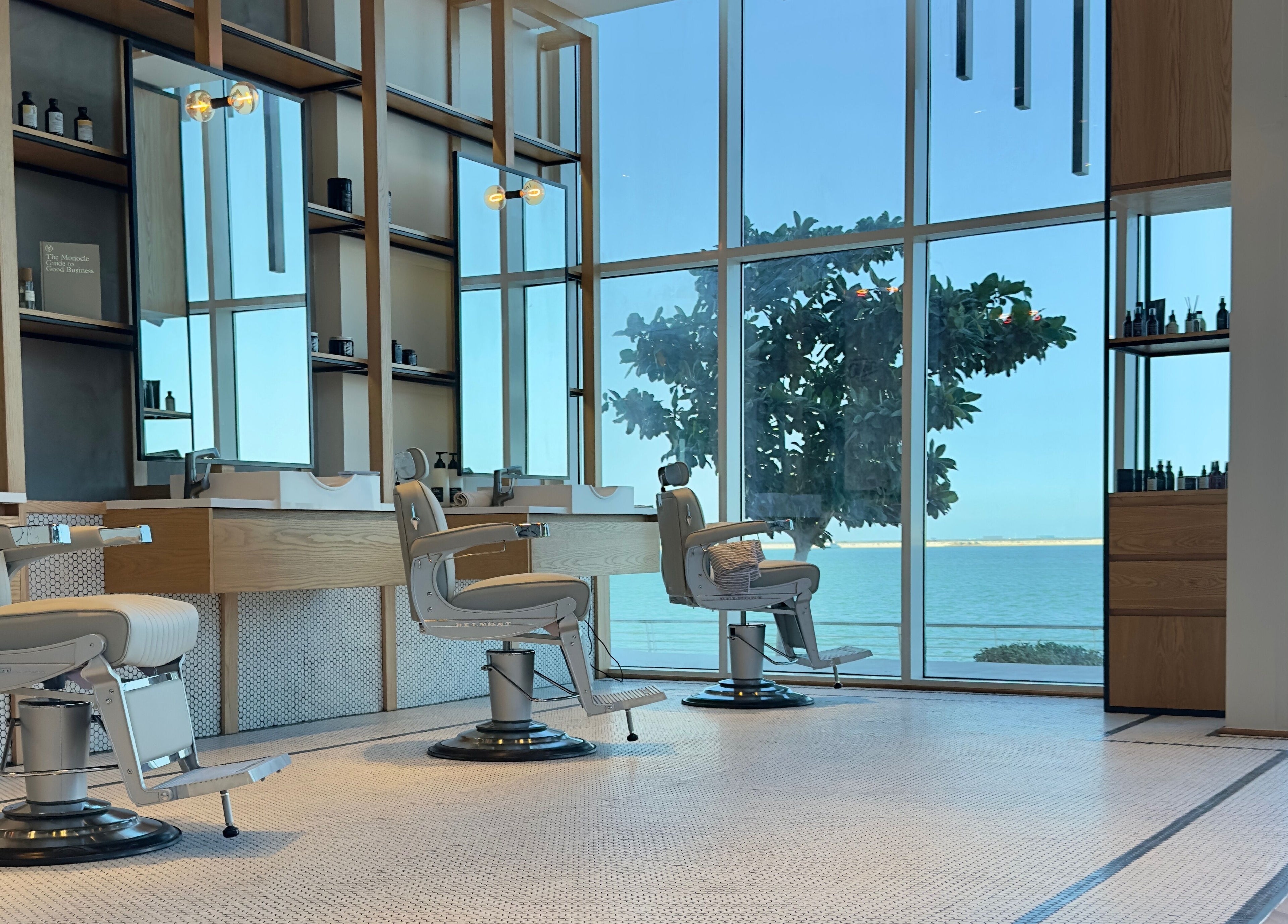 Elegant interior of Akin Barber & Shop AbuDhabi By The Creek showcasing barber chairs with a sea view, Abu Dhabi, AE.