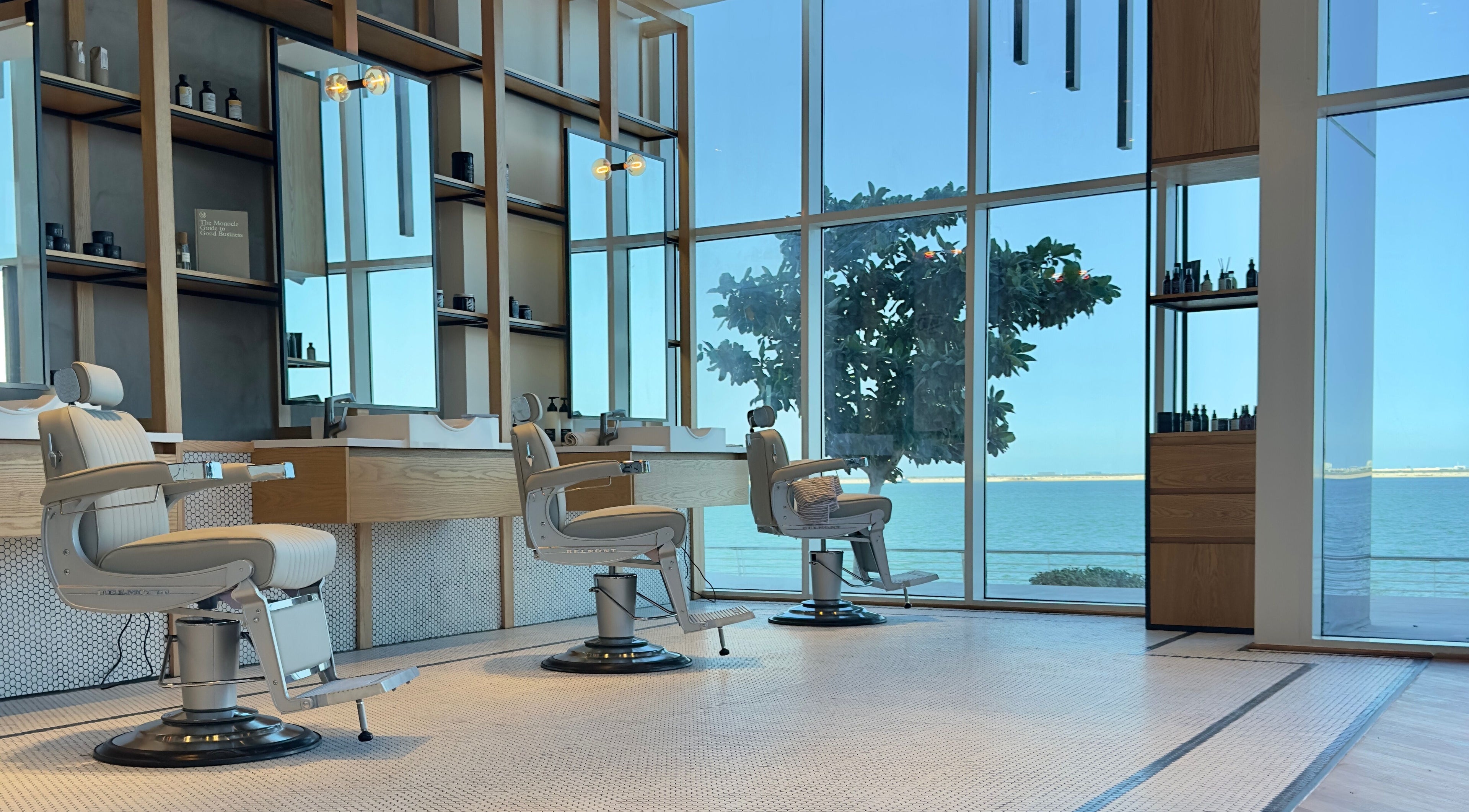 Elegant interior of Akin Barber & Shop AbuDhabi By The Creek showcasing barber chairs with a sea view, Abu Dhabi, AE.
