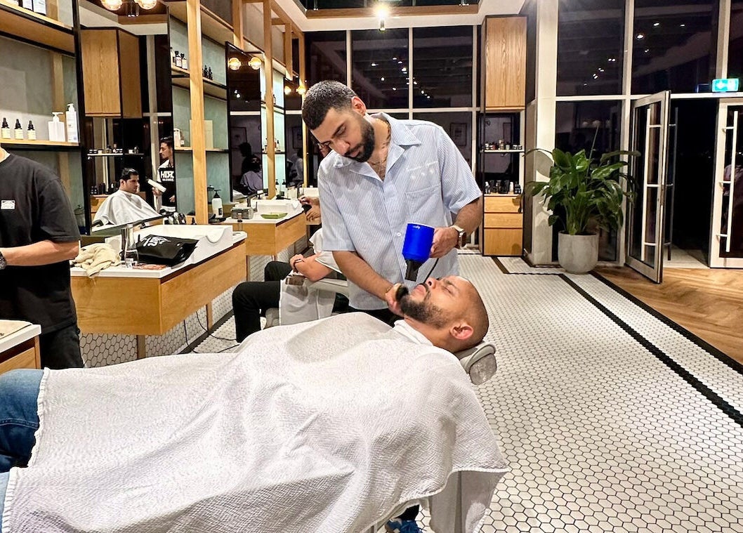 Barber styling a beard at Akin Barber & Shop AbuDhabi By The Creek, Abu Dhabi, AE in a modern, sleek interior.
