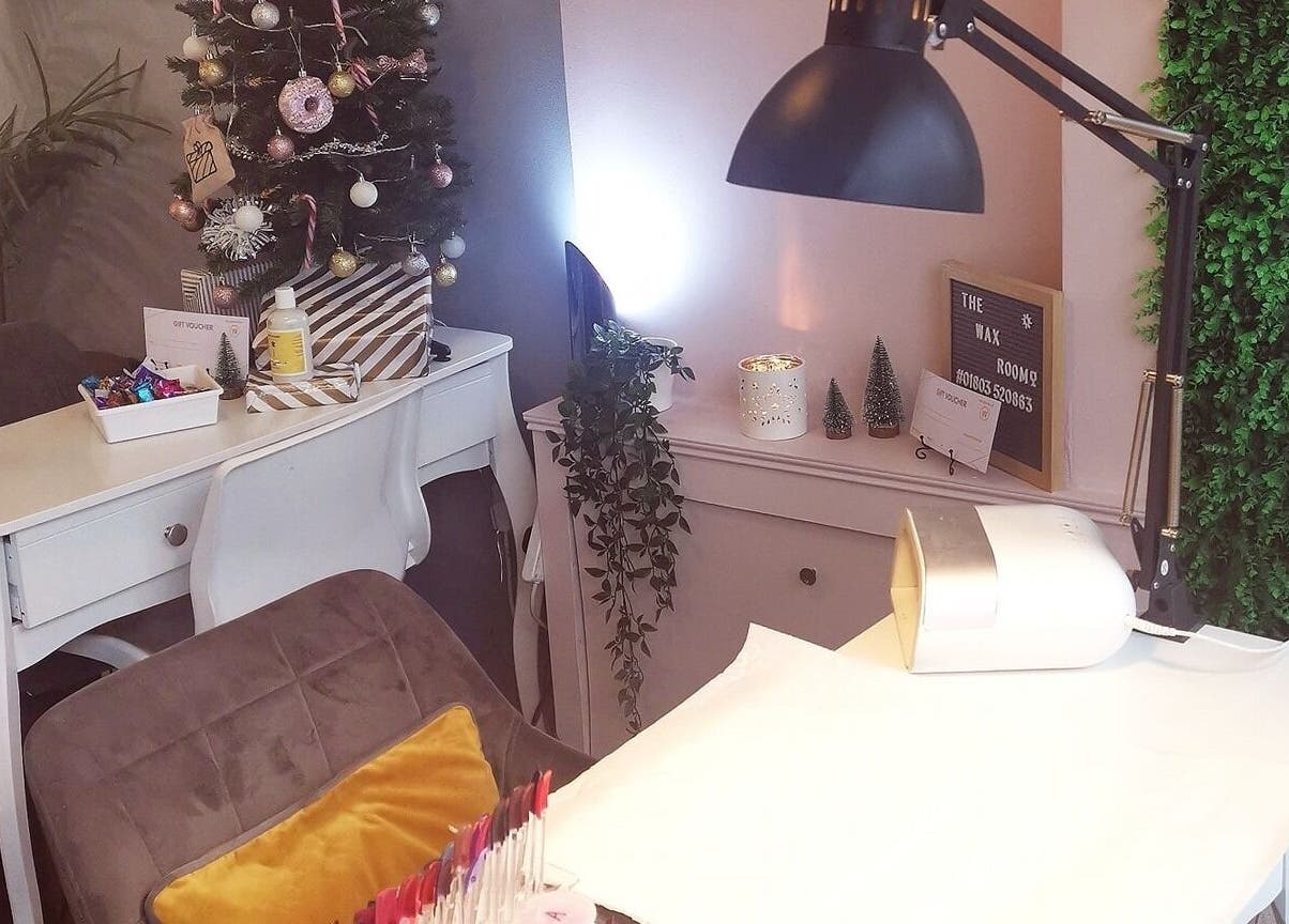 A cozy treatment area at The Wax Room in Paignton, England, GB, featuring festive decor and manicure setup.