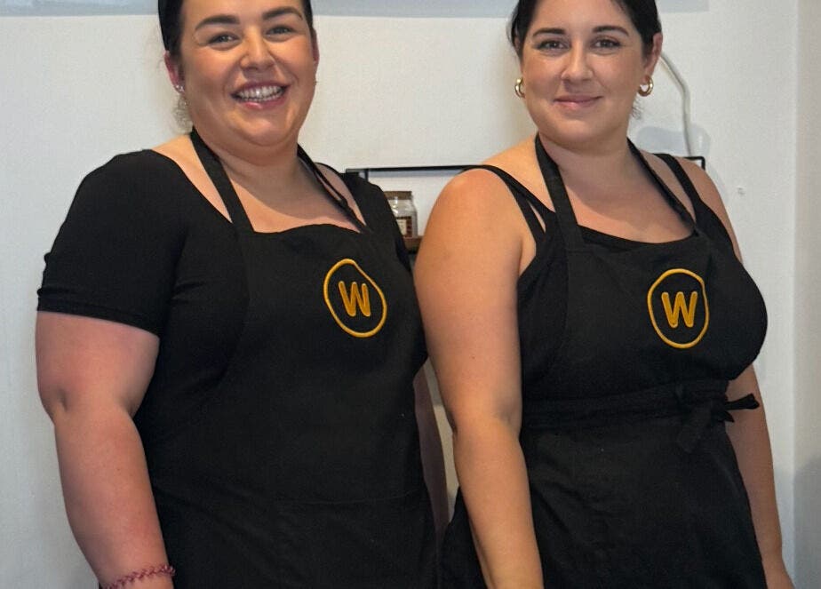 Two staff members smiling at The Wax Room, Paignton, England, GB in matching black aprons.