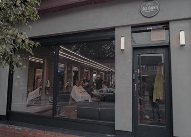 Exterior view of Old County Clondalkin barbershop in Dublin, County Dublin, IE, with customers inside.