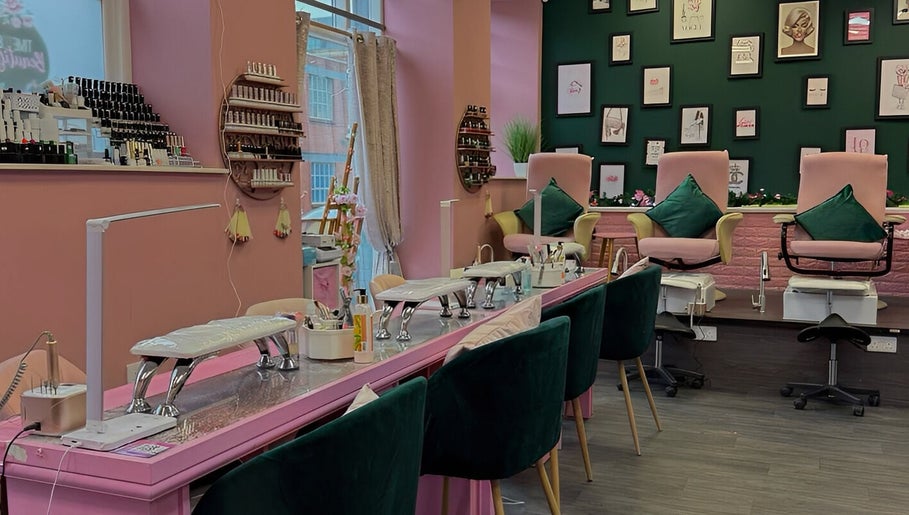 Interior of Nails And The City London in Birmingham, showcasing stylish pink and green decor with nail stations.