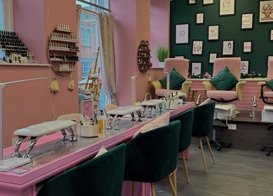 Interior of Nails And The City London in Birmingham, showcasing stylish pink and green decor with nail stations.