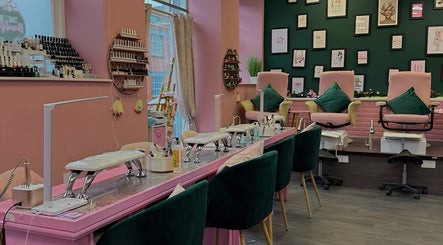 Interior of Nails And The City London in Birmingham, showcasing stylish pink and green decor with nail stations.