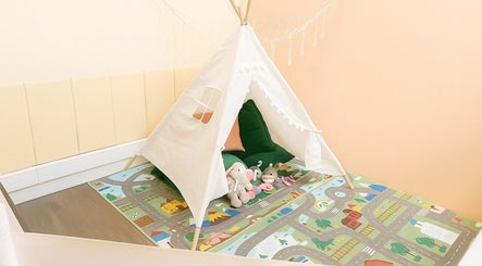 Charming teepee play area at Myrto Zafeiropoulou, Birmingham, England, GB with plush toys and colorful mat.