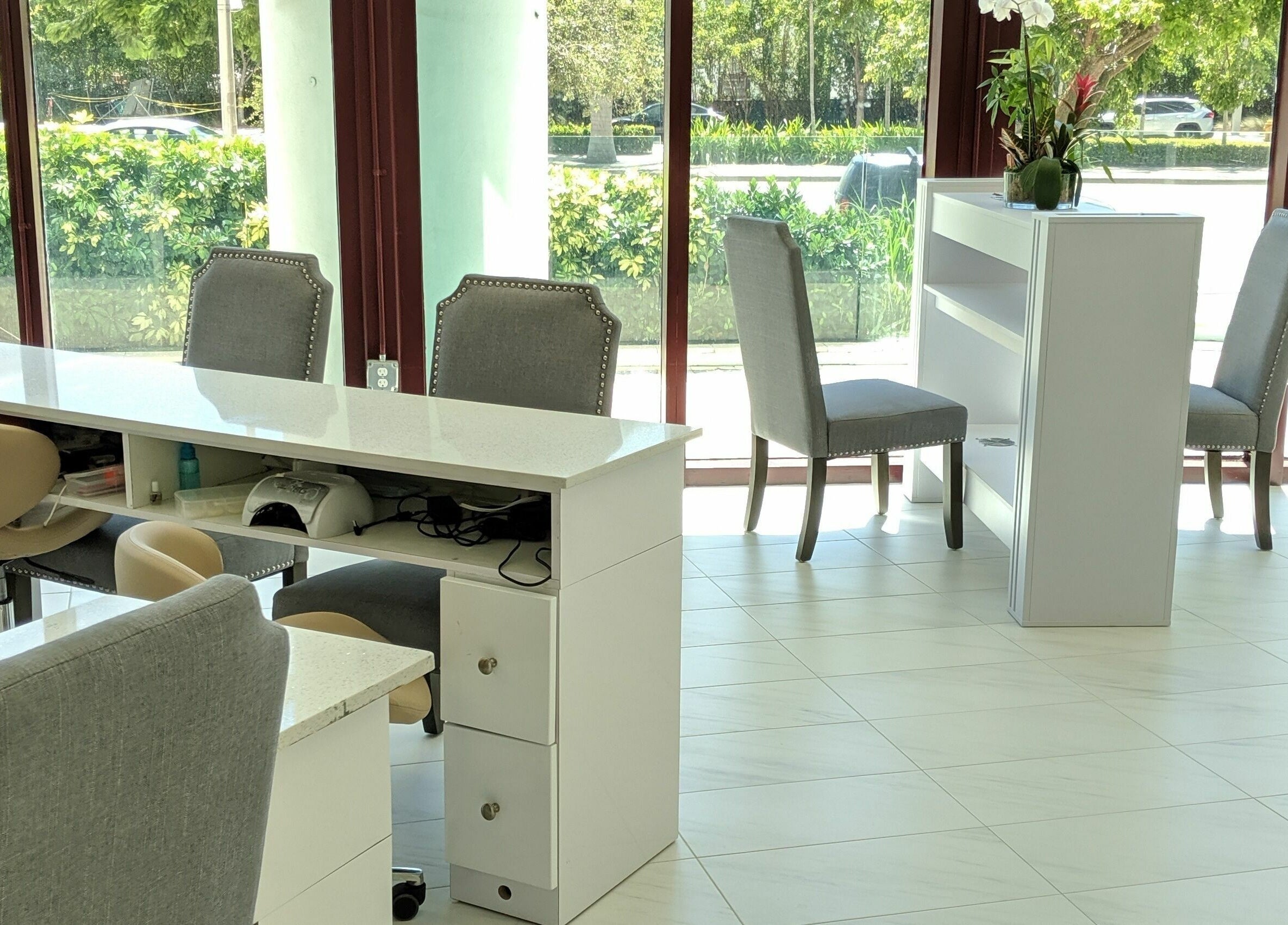 Bright, modern nail salon interior at The Nail Venue, Miami, Florida, US with sleek white manicure stations.