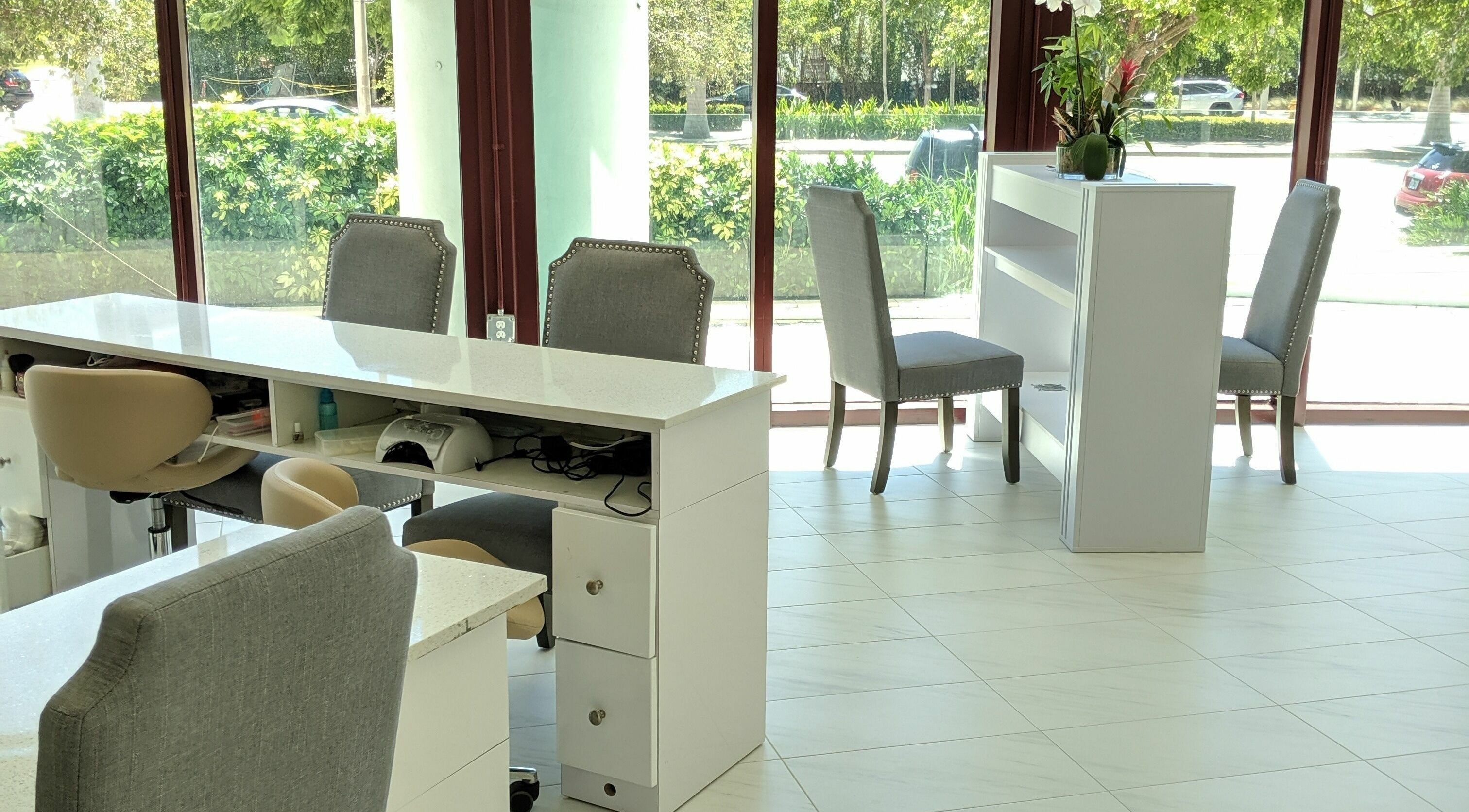 Bright, modern nail salon interior at The Nail Venue, Miami, Florida, US with sleek white manicure stations.