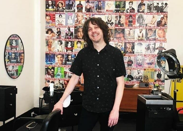 Interior of Paradise Cutters in Melbourne, Victoria, AU, featuring a stylist in front of a vibrant wall.