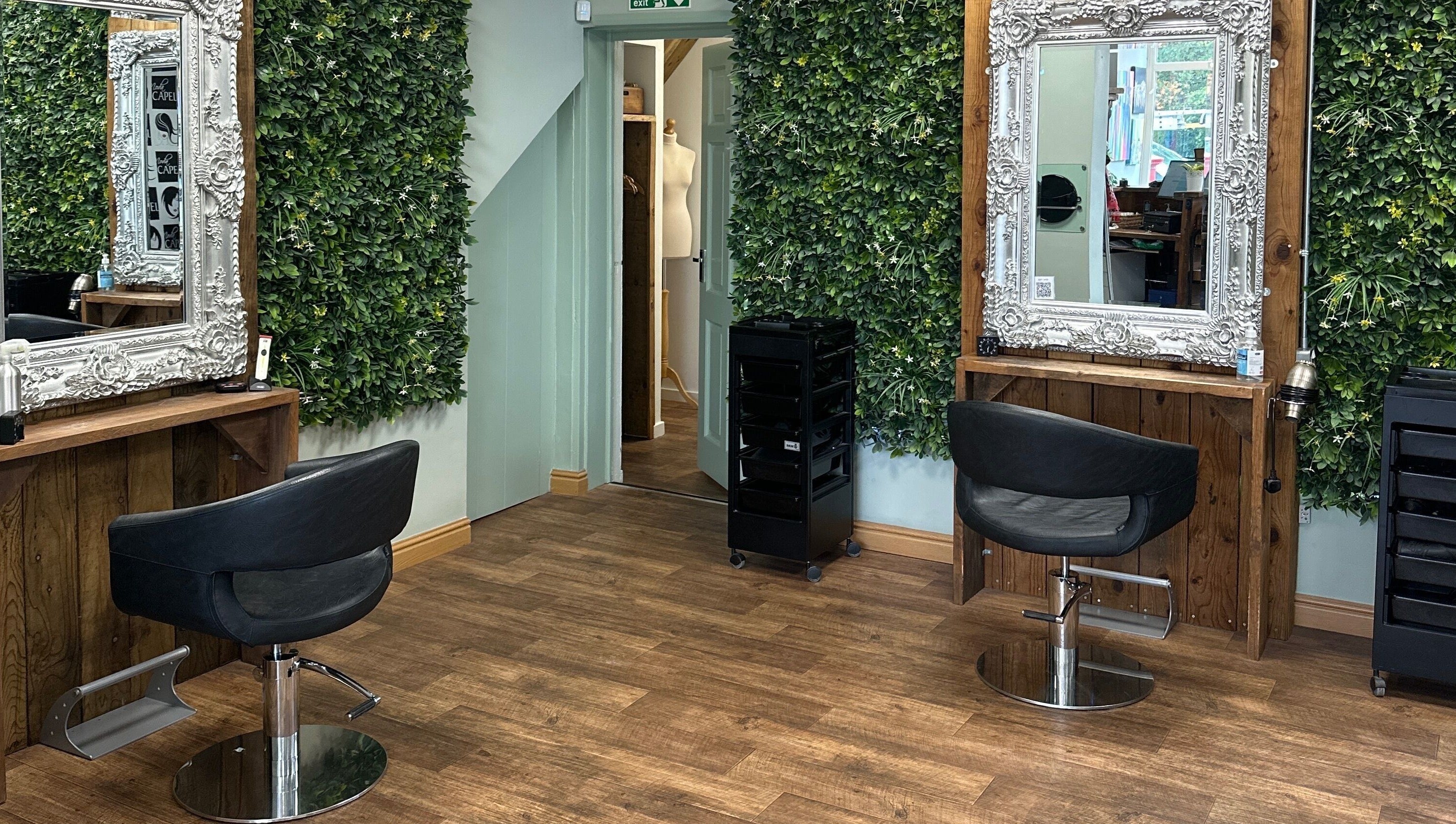 Chic salon space at Moda Capelli, Ashington, England, GB, featuring elegant mirrors and lush green walls.