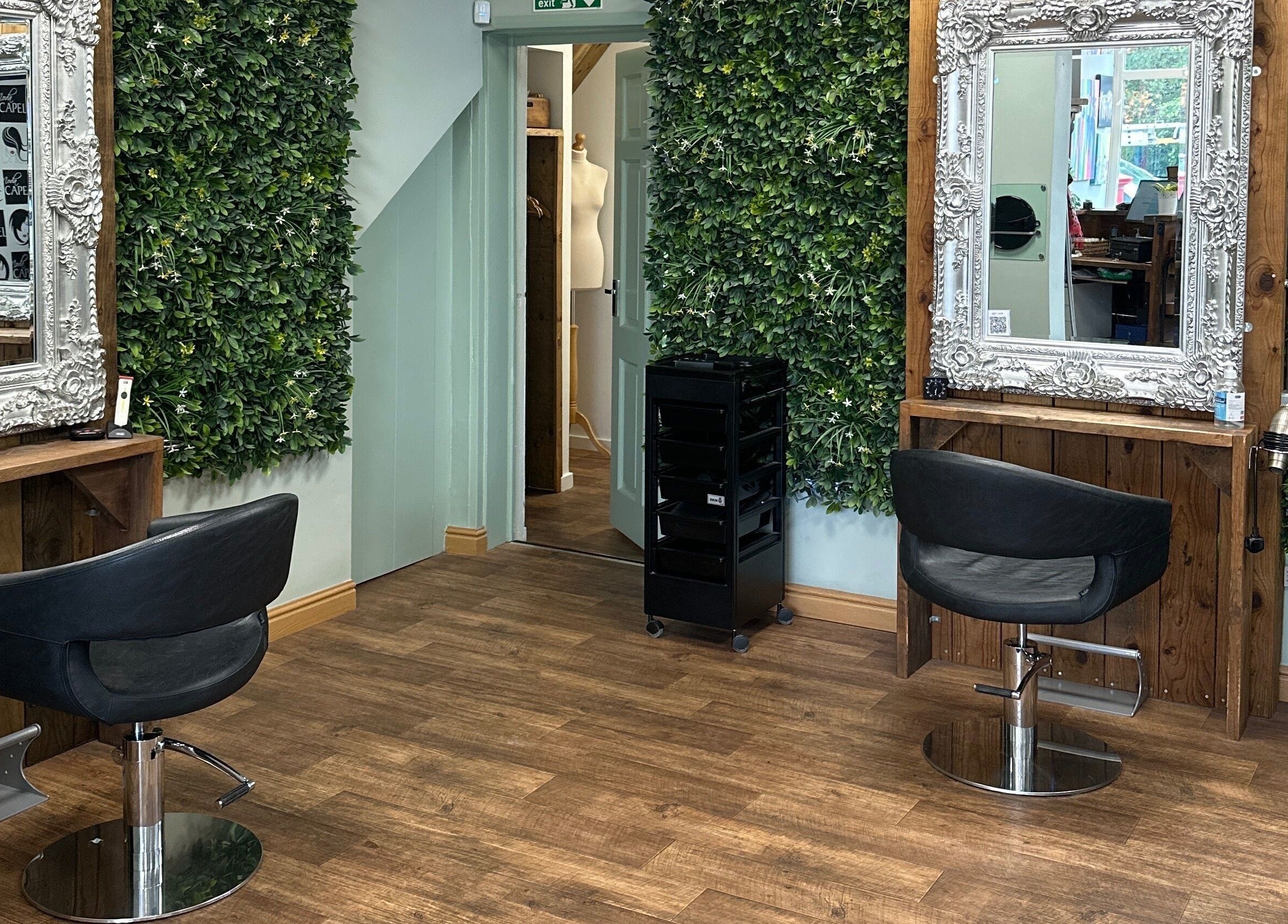 Chic salon space at Moda Capelli, Ashington, England, GB, featuring elegant mirrors and lush green walls.
