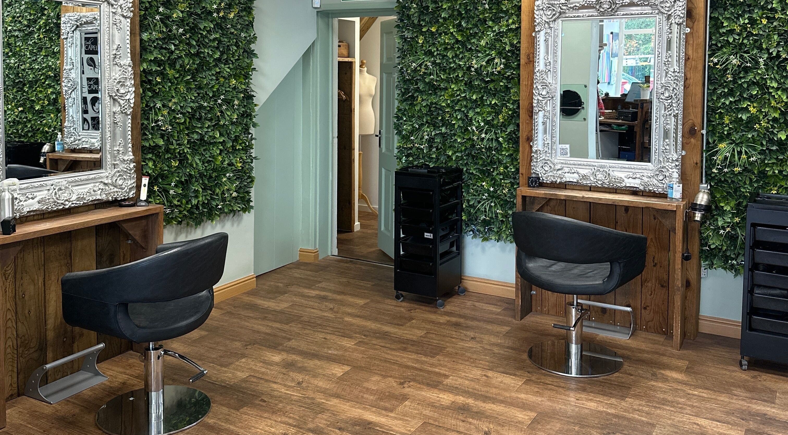 Chic salon space at Moda Capelli, Ashington, England, GB, featuring elegant mirrors and lush green walls.