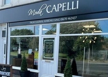 Moda Capelli storefront in Ashington, England, GB, displaying modern salon design with large glass windows.