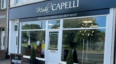 Moda Capelli storefront in Ashington, England, GB, displaying modern salon design with large glass windows.