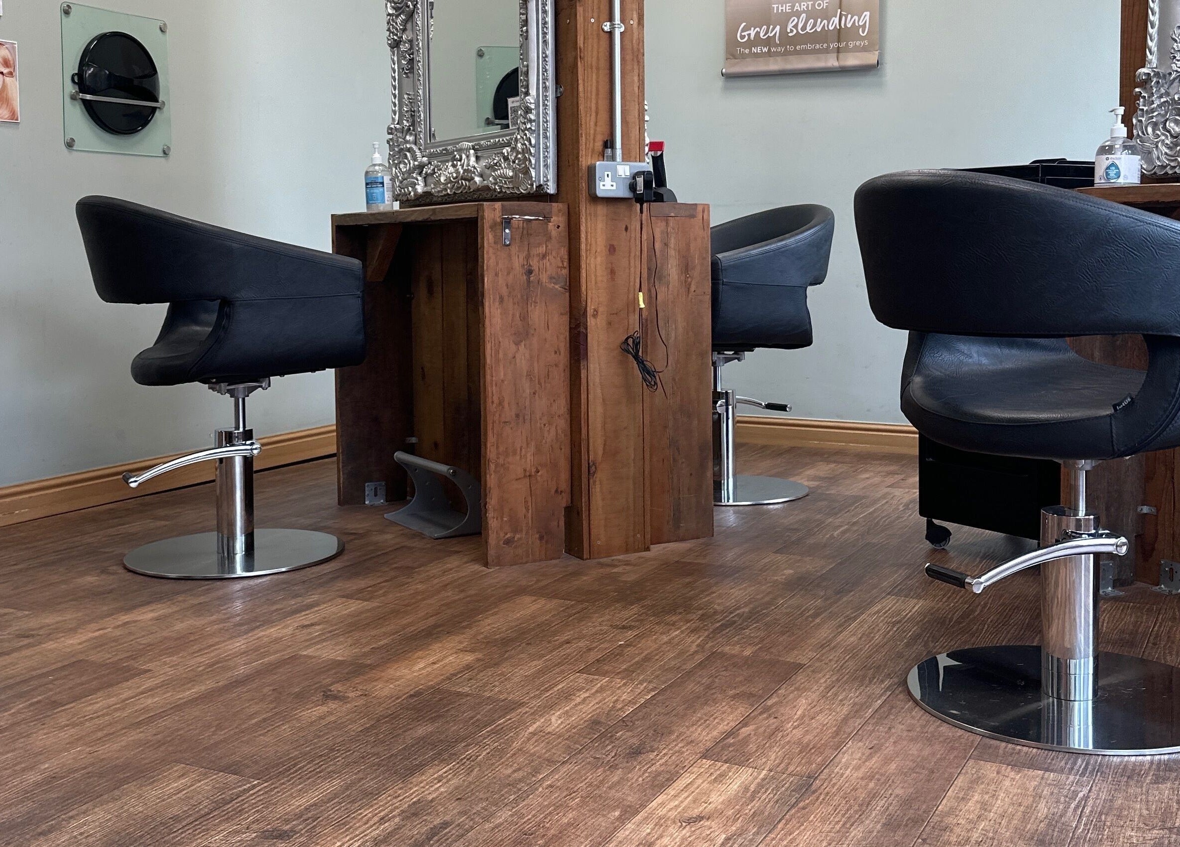 Elegant styling stations at Moda Capelli, Ashington, England, GB, featuring sleek black chairs and ornate mirrors.