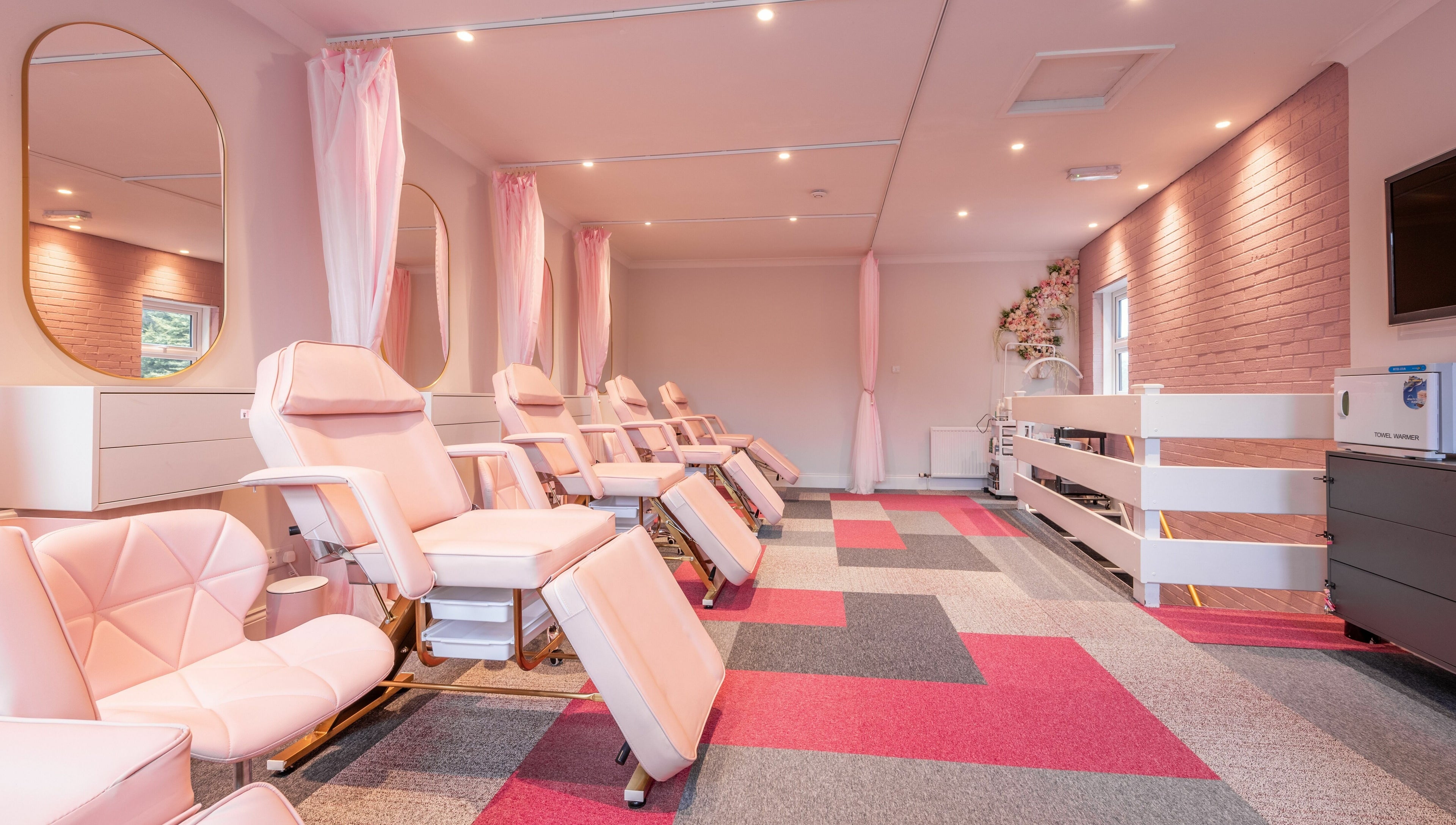 Spacious beauty treatment room at Pink. Academy, Worsley, England, GB with elegant pink chairs and bright decor.