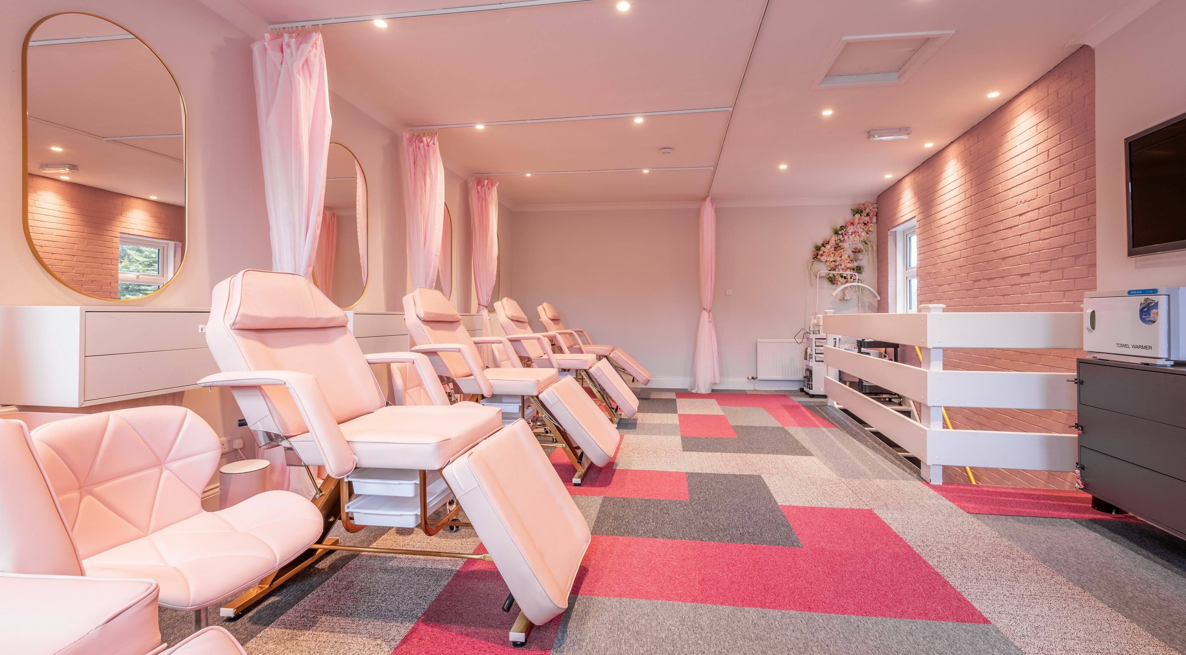 Spacious beauty treatment room at Pink. Academy, Worsley, England, GB with elegant pink chairs and bright decor.