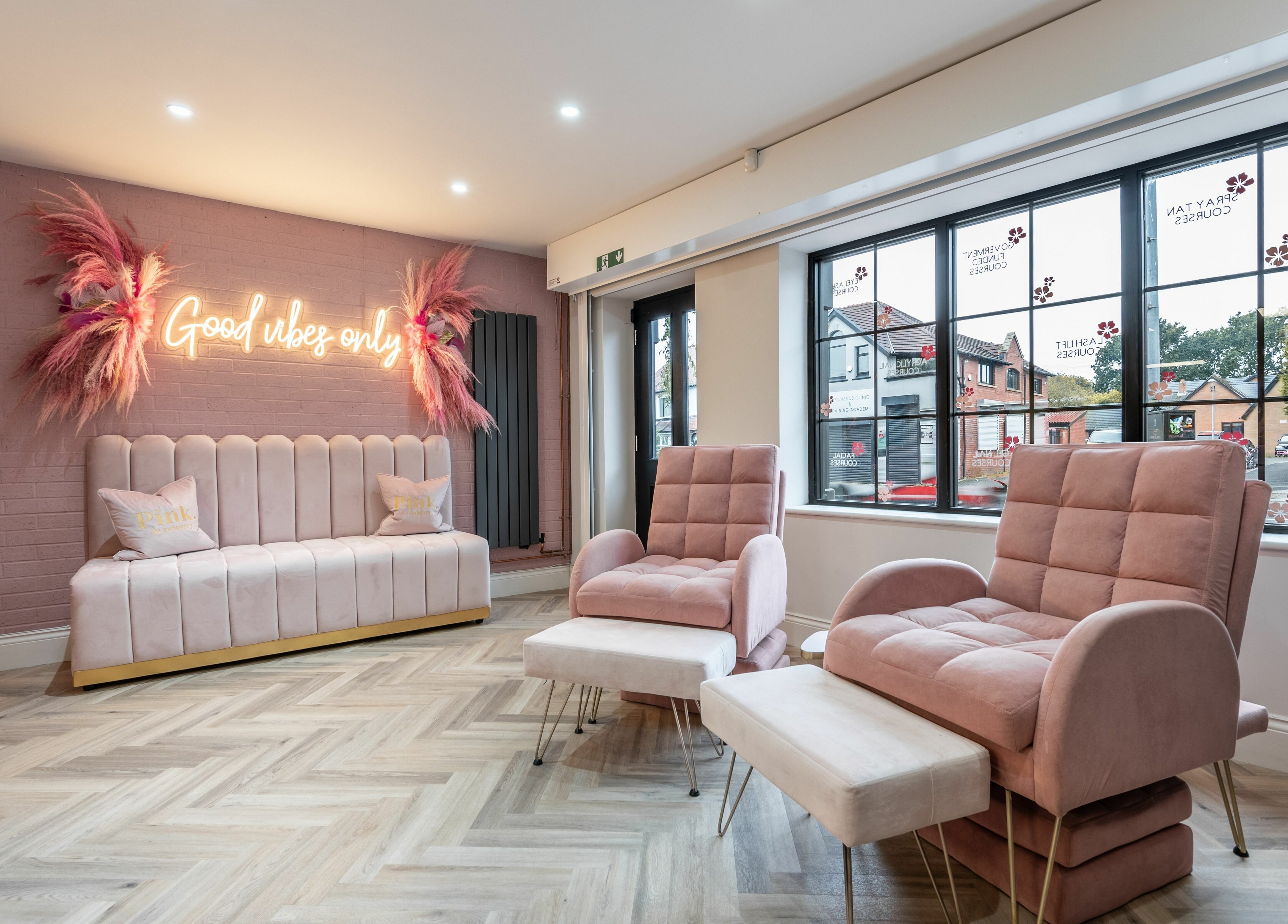 Chic lounge area at Pink. Academy in Worsley, England, GB with stylish pink chairs and neon sign.