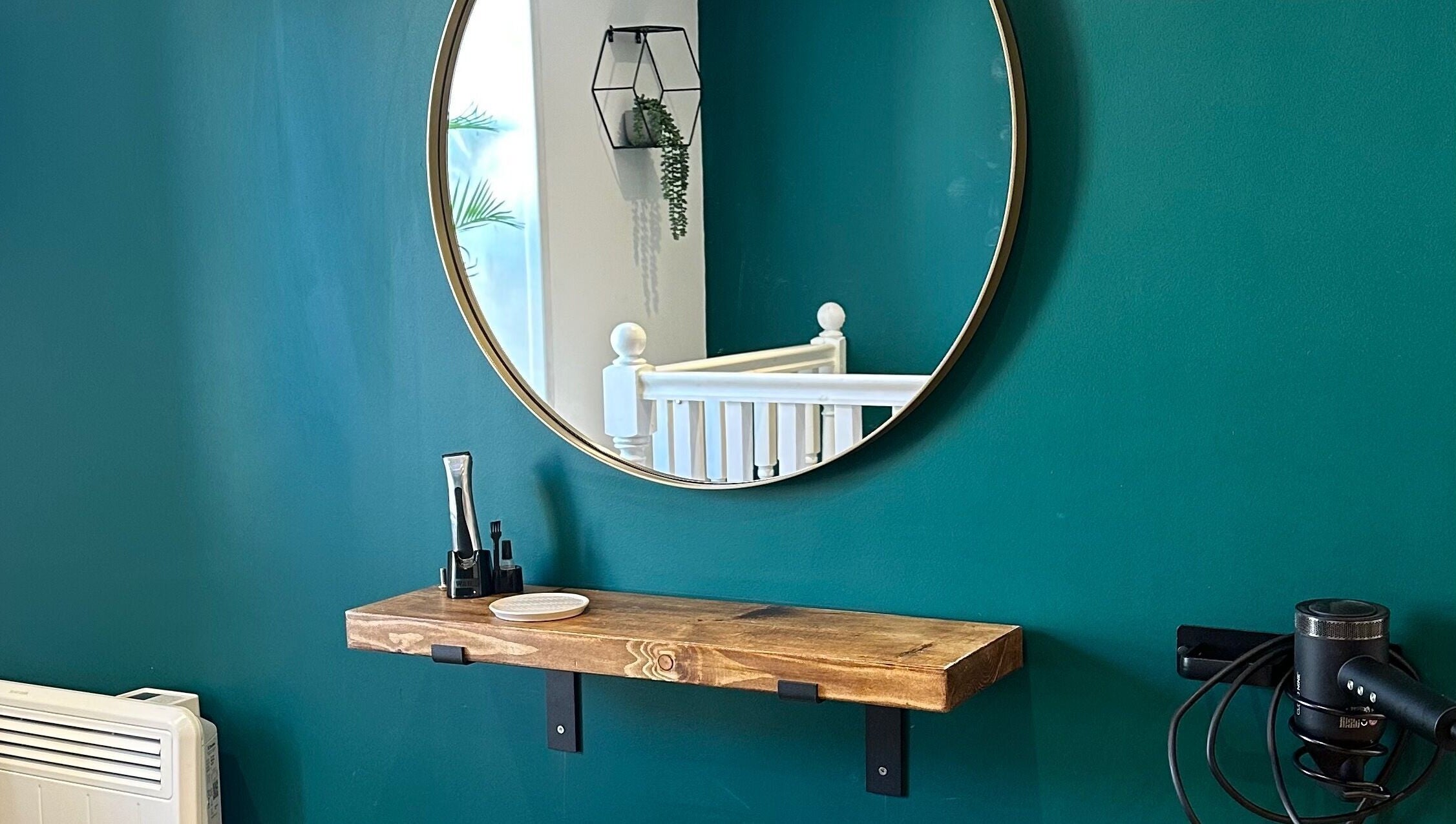 Elegant salon setup with a round mirror and wooden shelf at Fringe, Bolsover, England, GB.