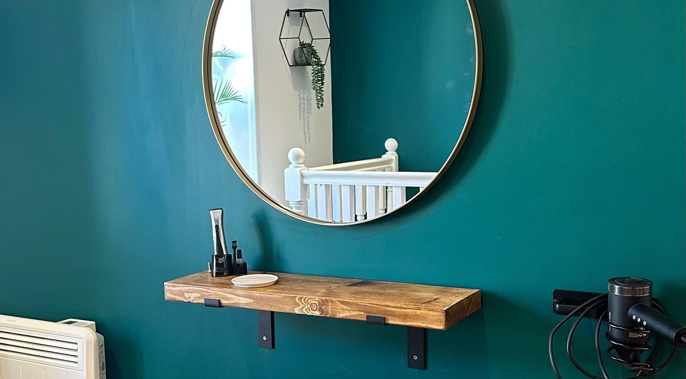 Elegant salon setup with a round mirror and wooden shelf at Fringe, Bolsover, England, GB.