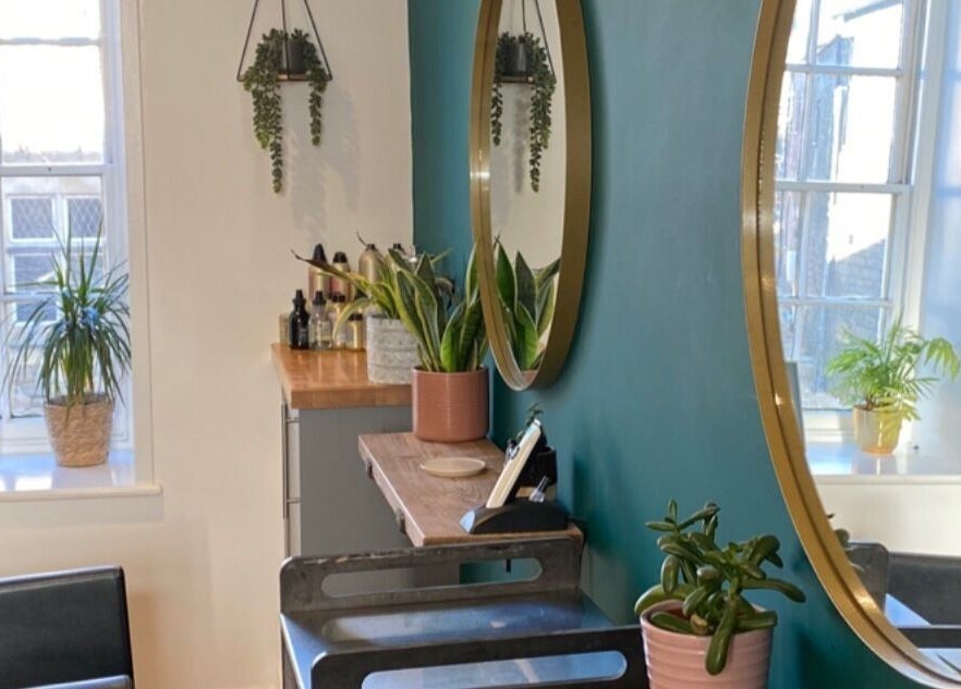 Elegant beauty salon corner at Fringe, Bolsover, England, GB with round mirrors and lush potted plants.