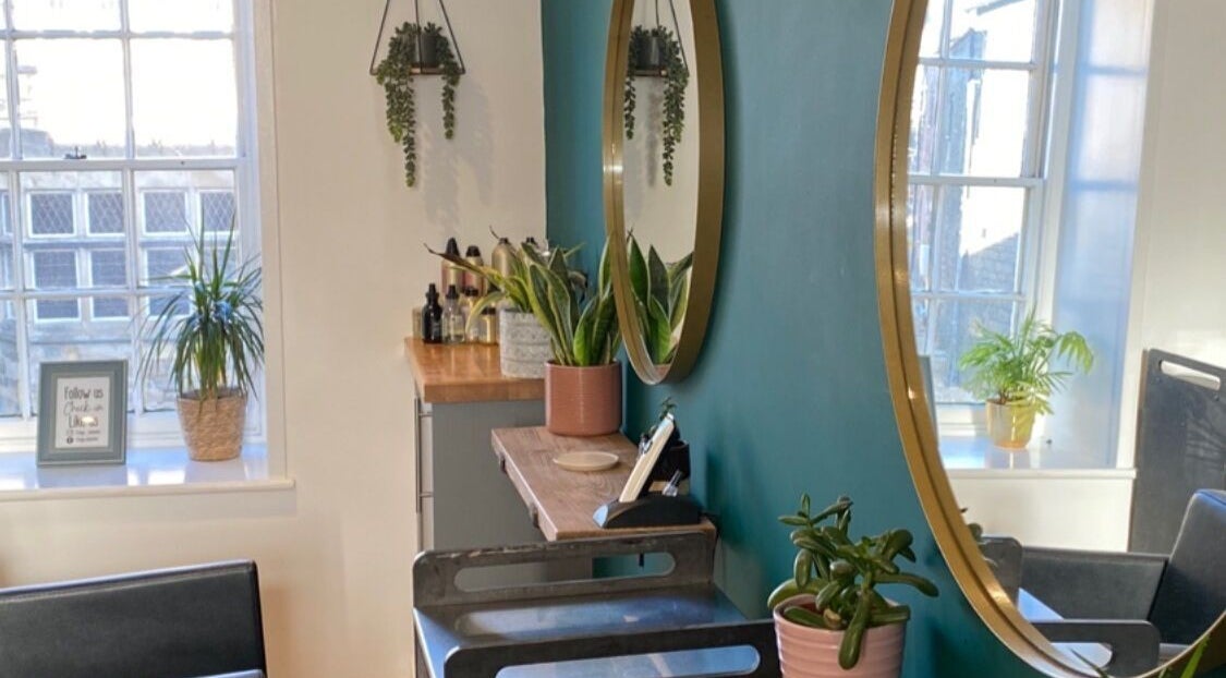 Elegant beauty salon corner at Fringe, Bolsover, England, GB with round mirrors and lush potted plants.