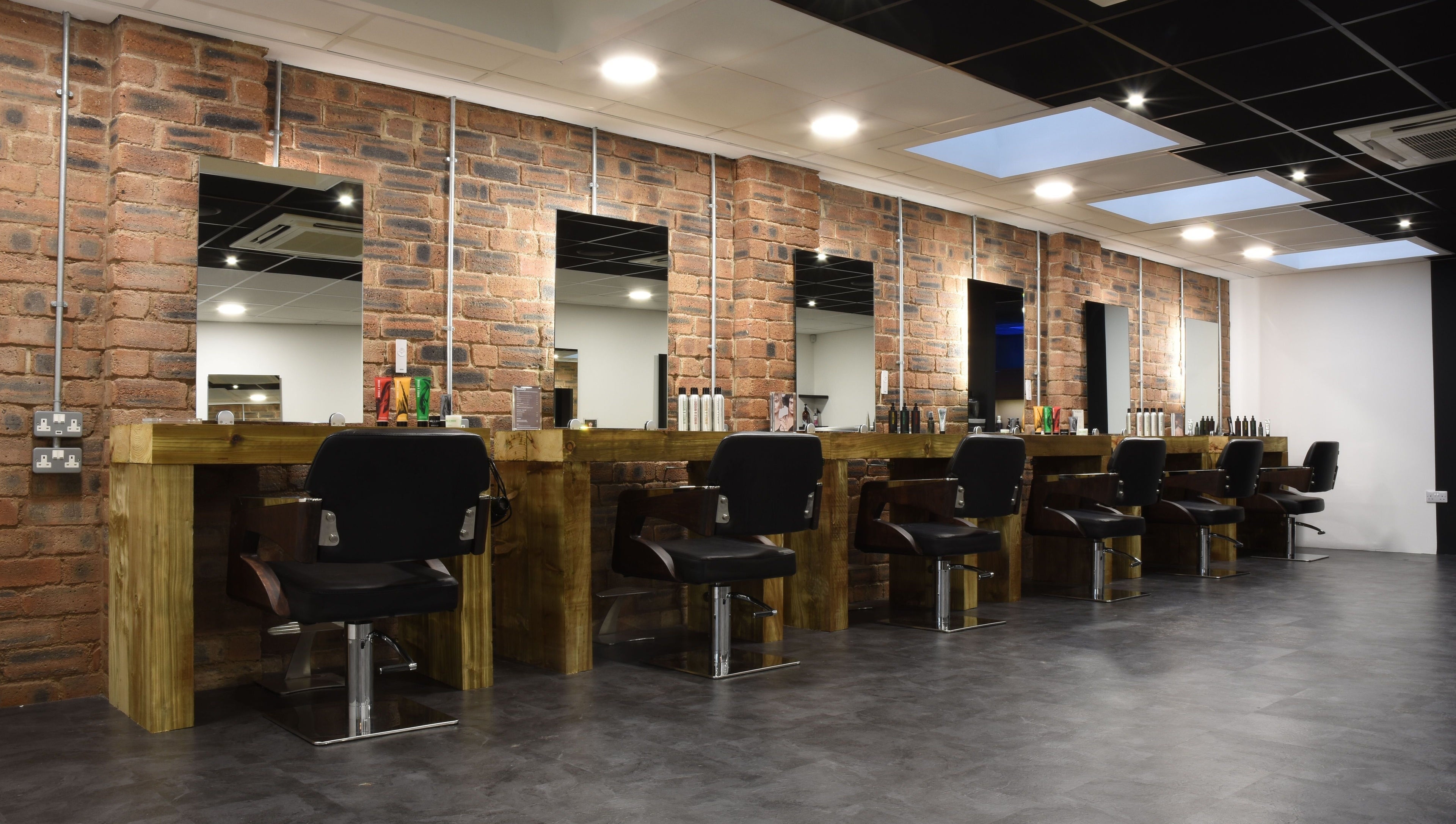 Contemporary salon setup at Nelson Brown in Dumfries, Scotland, GB with modern styling chairs and wooden stations.