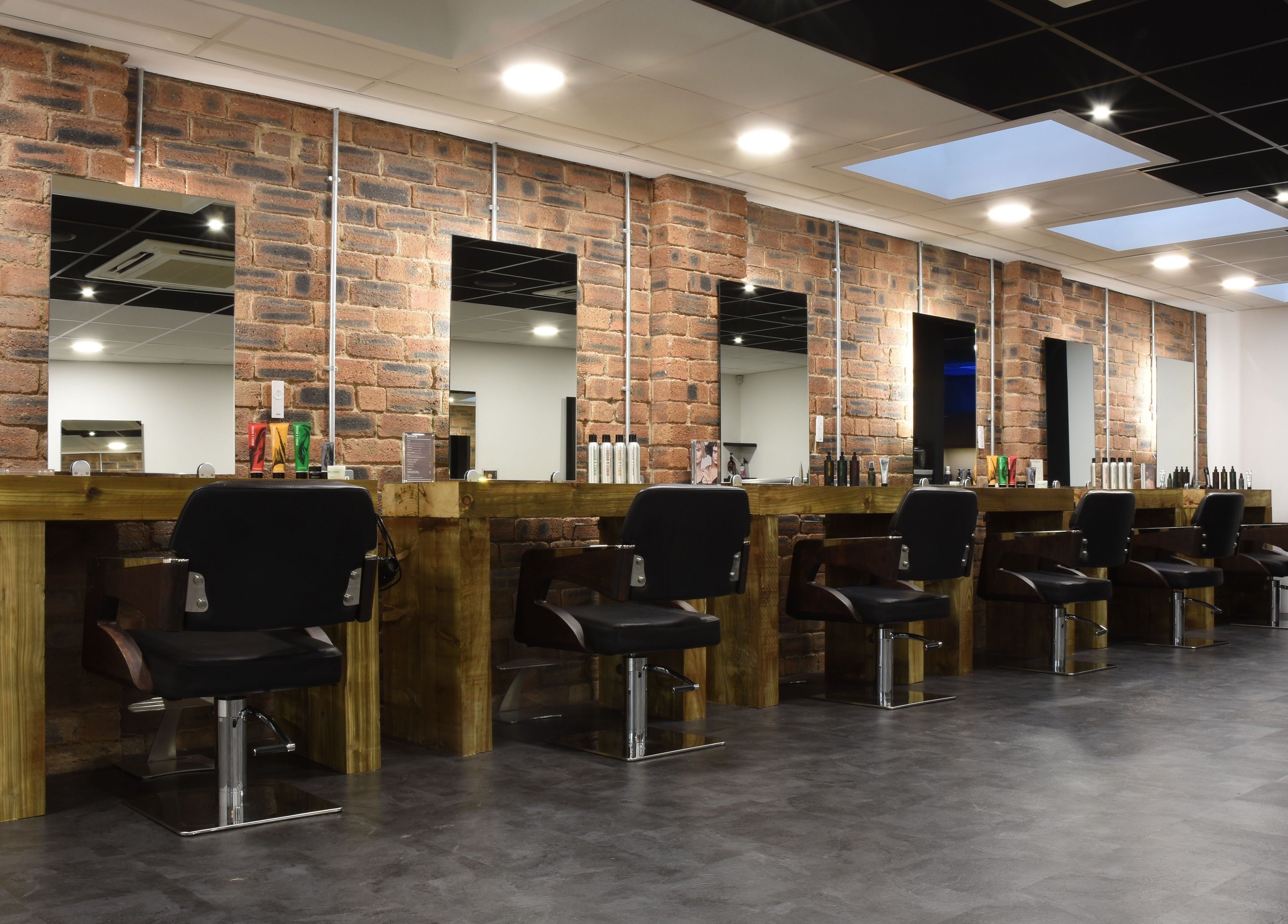 Contemporary salon setup at Nelson Brown in Dumfries, Scotland, GB with modern styling chairs and wooden stations.