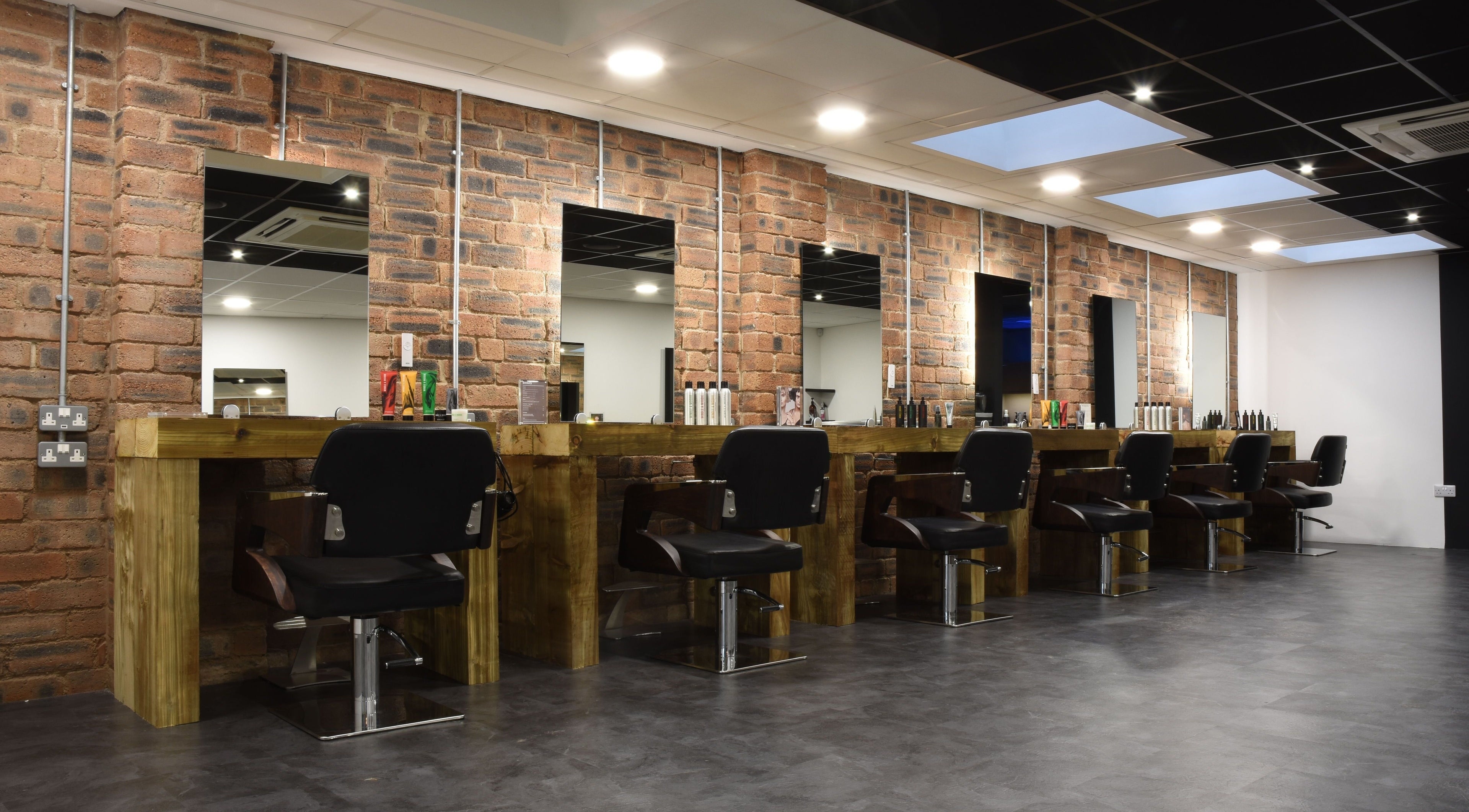 Contemporary salon setup at Nelson Brown in Dumfries, Scotland, GB with modern styling chairs and wooden stations.