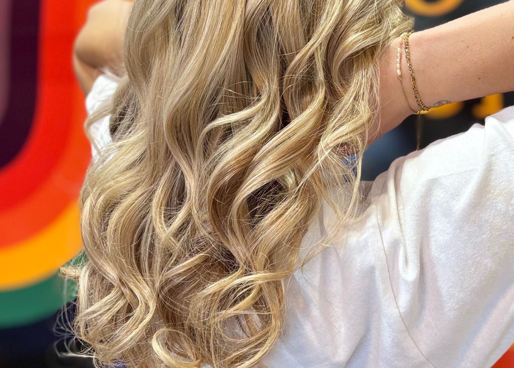 Blonde curls highlighted against a vibrant backdrop at Yo Barbra, Bacchus Marsh, Victoria, AU.