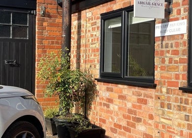 Entrance of Abigail Grace Beauty in Rugby, England, GB with a parked car and brick facade.