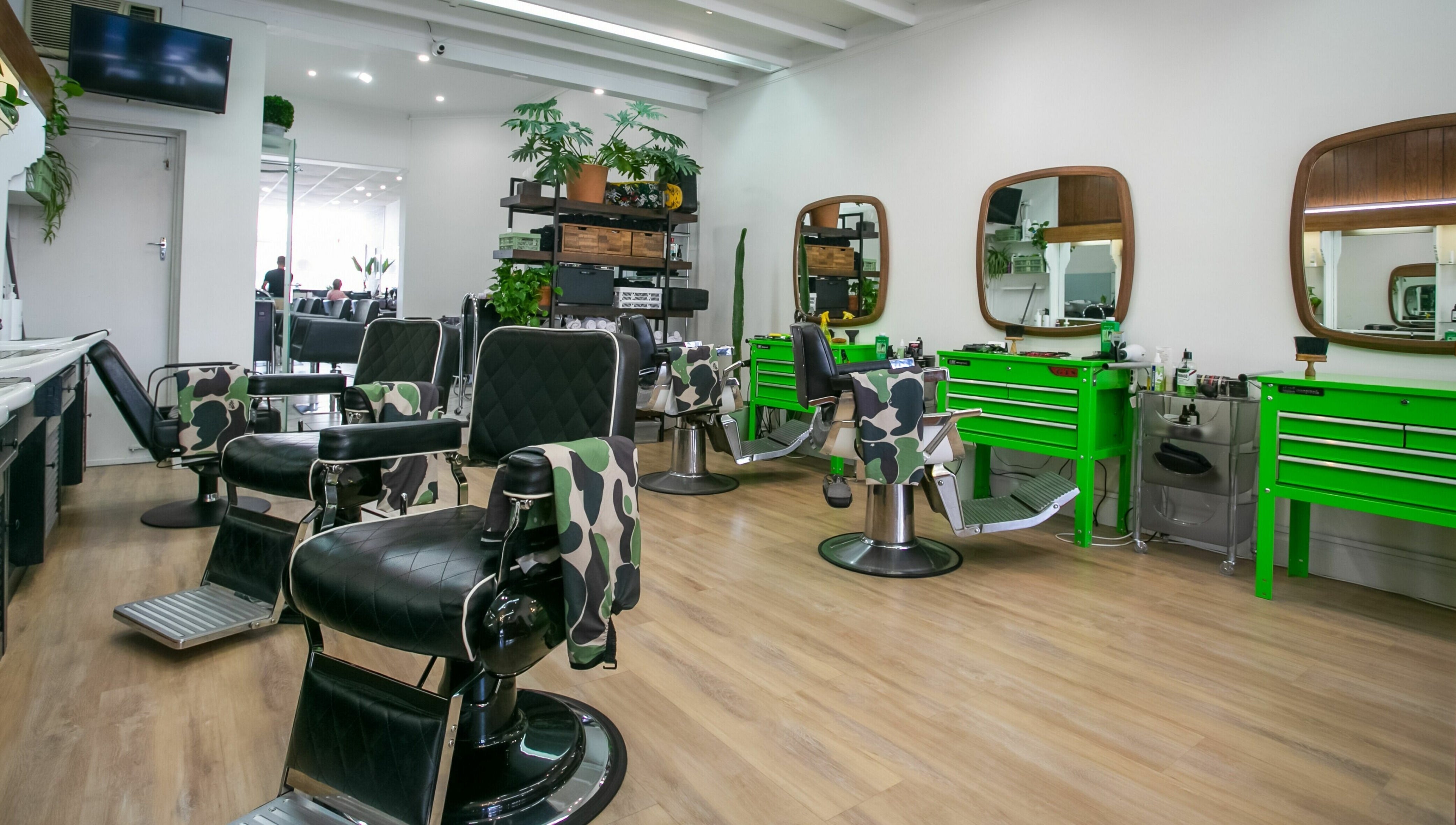 Chic interior of Daniel’s Barbershop in Melbourne, Victoria, AU with stylish chairs and green tool stations.