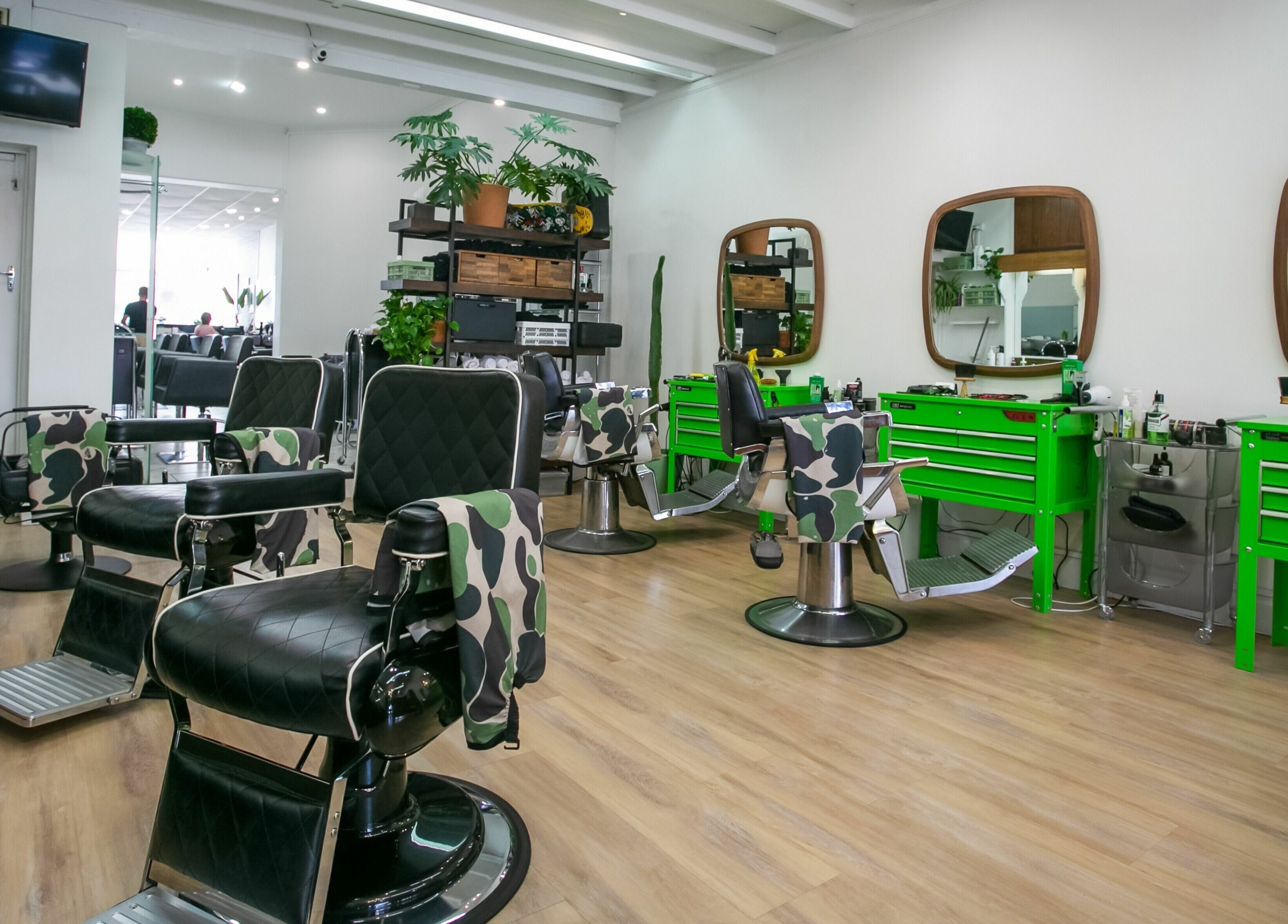 Chic interior of Daniel’s Barbershop in Melbourne, Victoria, AU with stylish chairs and green tool stations.