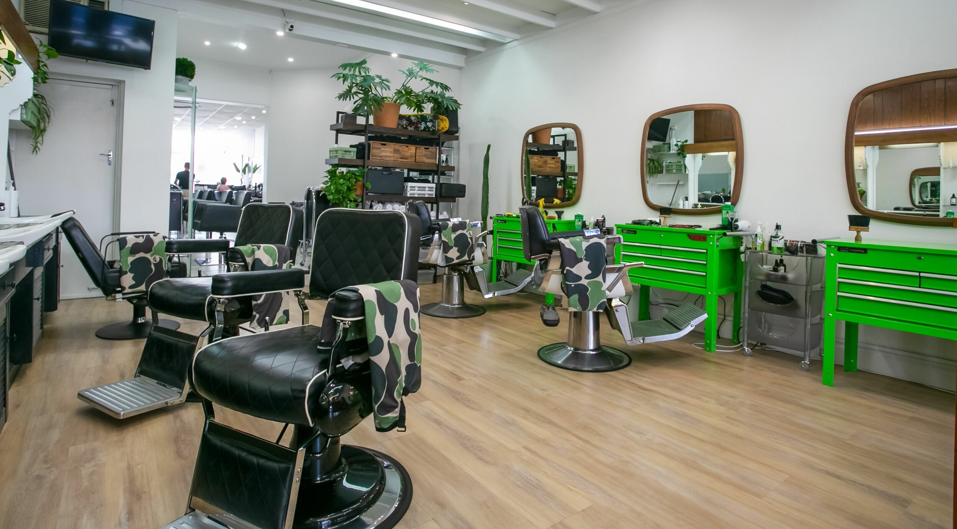 Chic interior of Daniel’s Barbershop in Melbourne, Victoria, AU with stylish chairs and green tool stations.