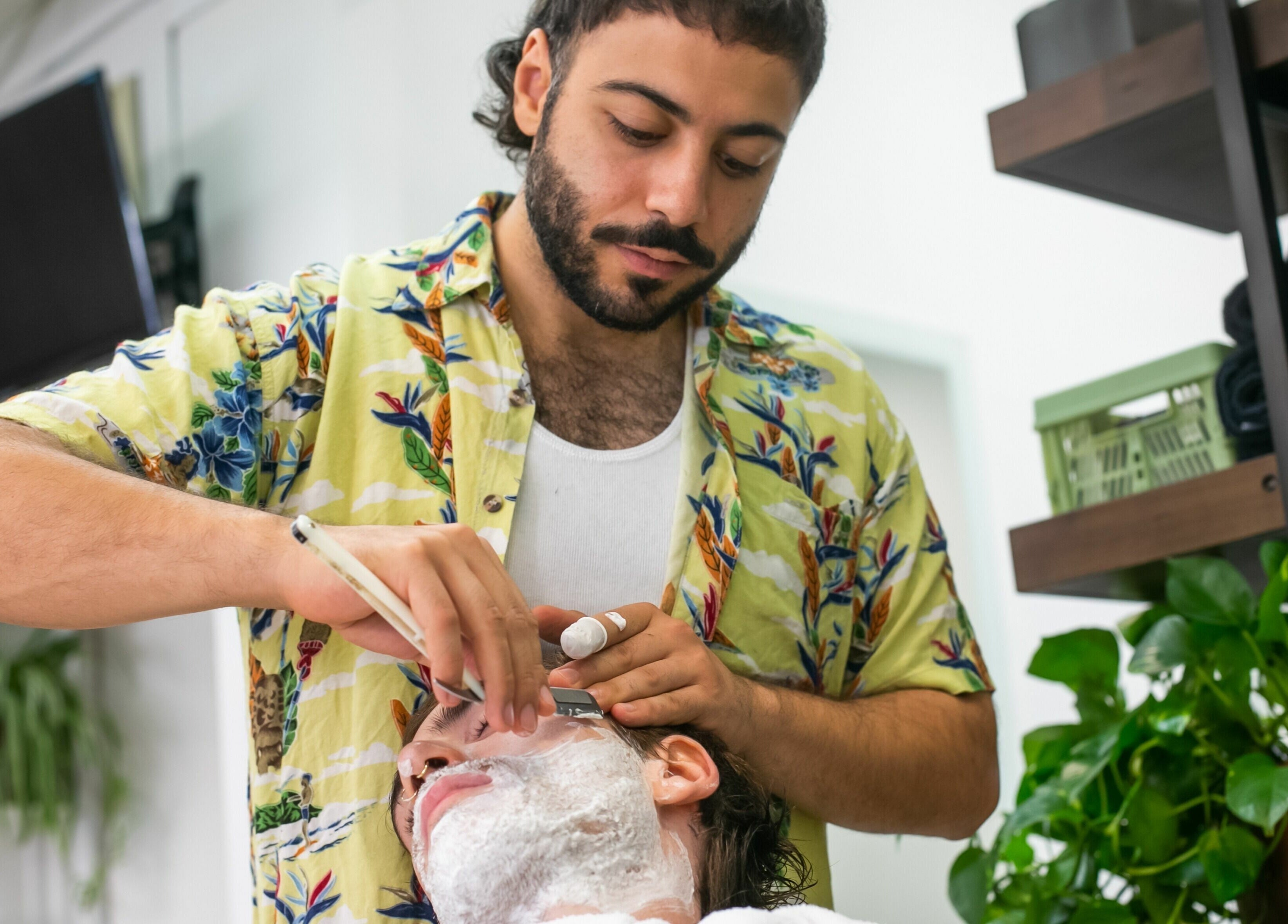 Barber at Daniel’s Barbershop in Melbourne, Victoria, AU expertly shaves a client’s beard.